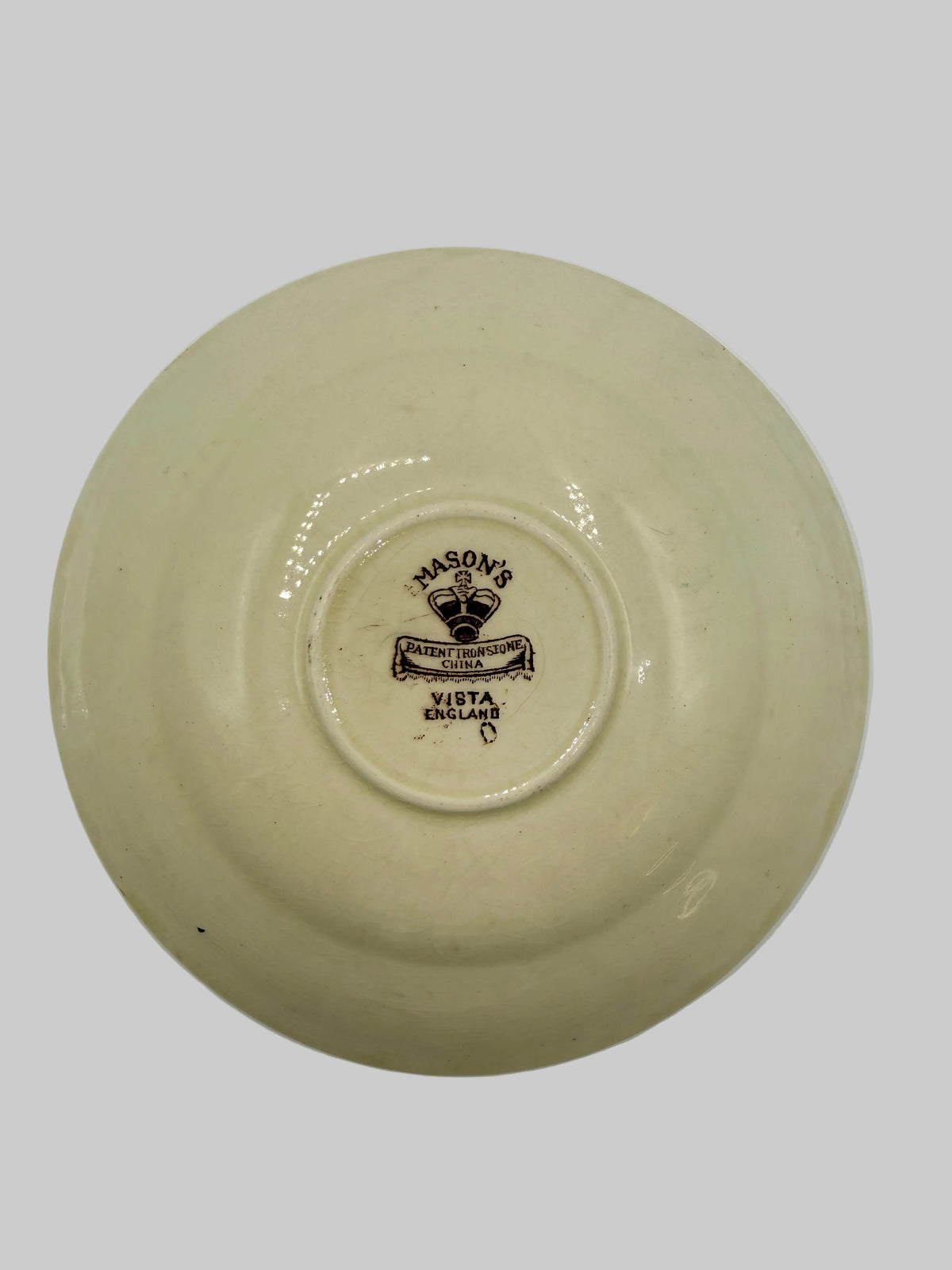 A vintage cream-colored ceramic plate shown from the bottom, featuring a dark brown printed logo in the center that reads 'BOSTON WAREHOUSE'.