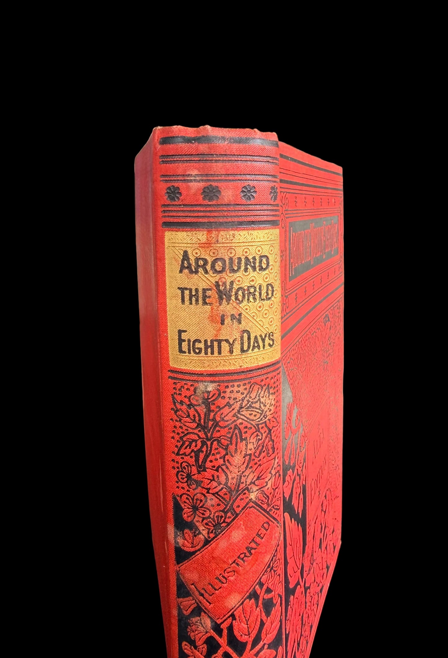 Red book titled 'Around the World in Eighty Days' on a table outdoors.