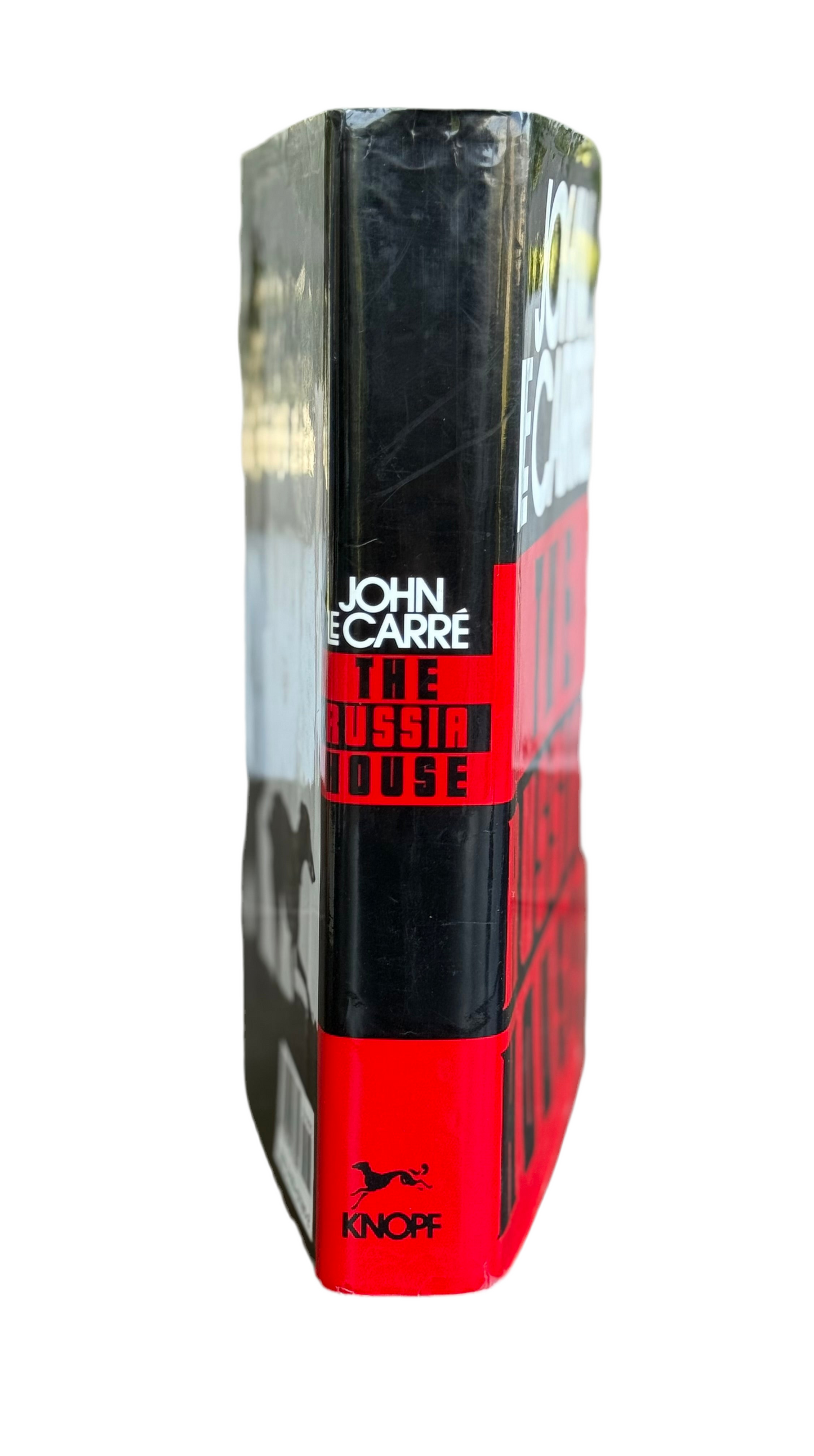 Book cover of 'The Russia House' by John Carre with black and red design.