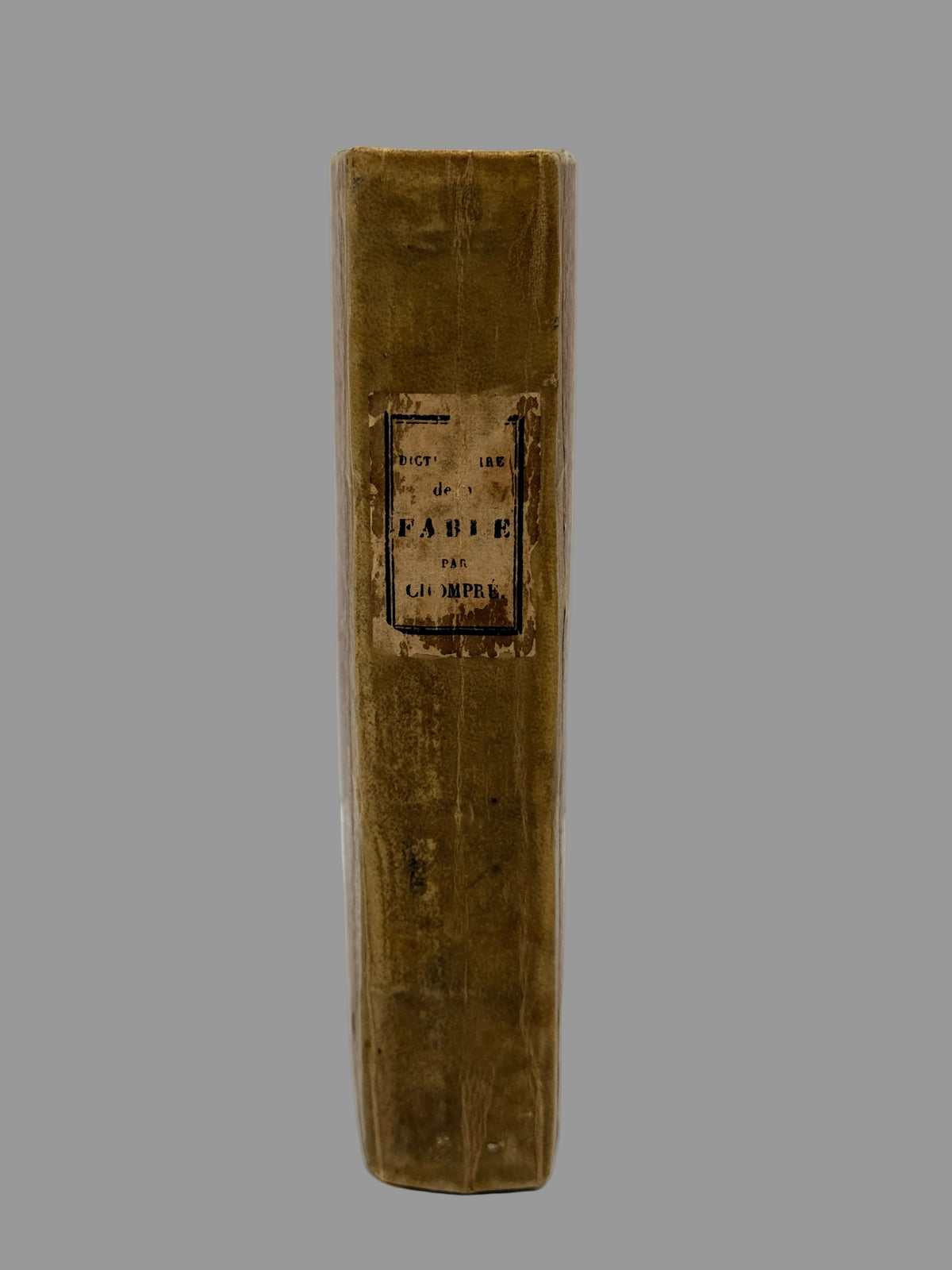 A vintage hardcover book standing upright, showing its brown leather-bound spine with a central paper label reading 'Le Livre de la Fabrique des Chiffres' and '1840'.