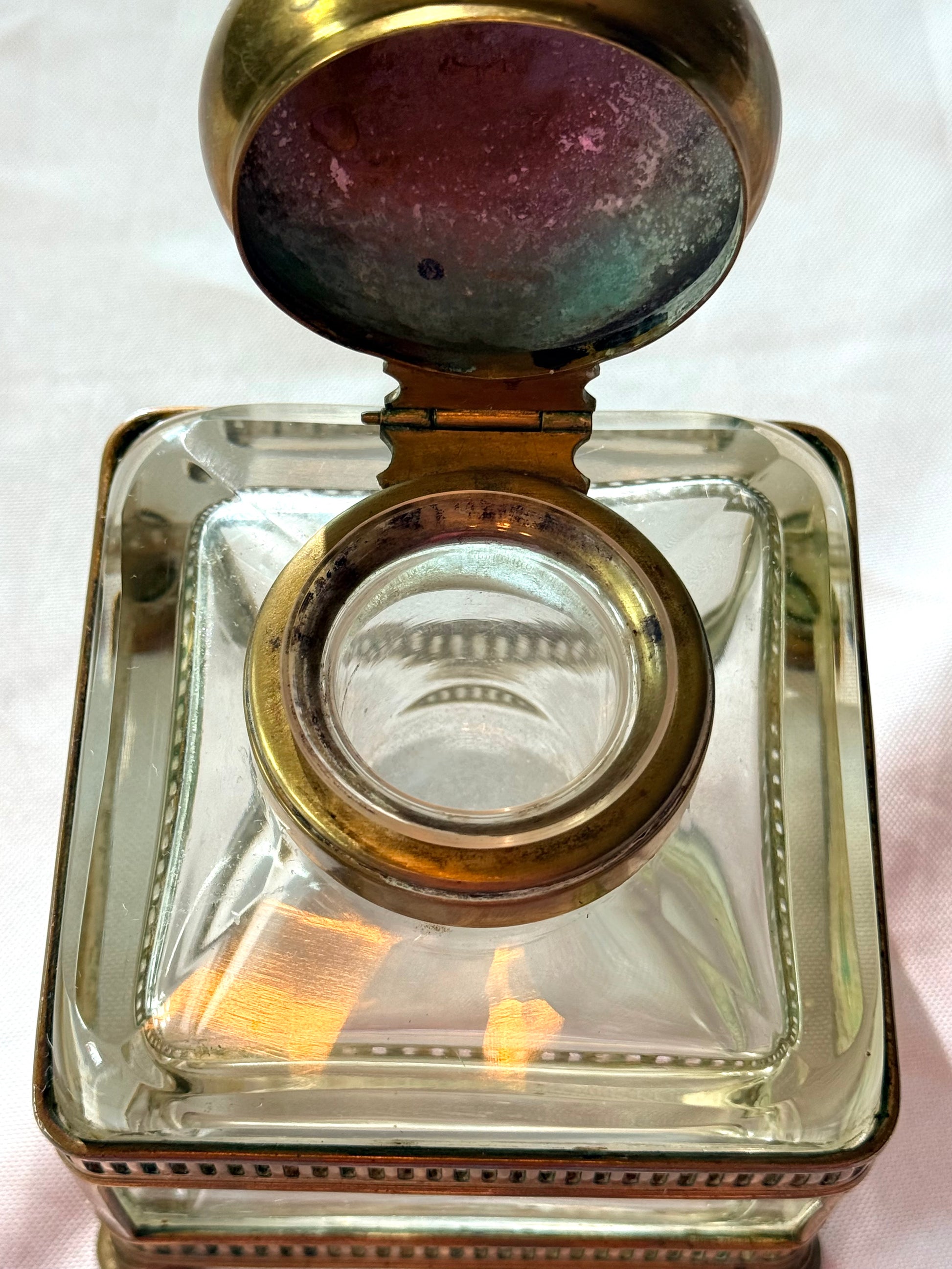 Vintage glass inkwell with a gold lid on a white background