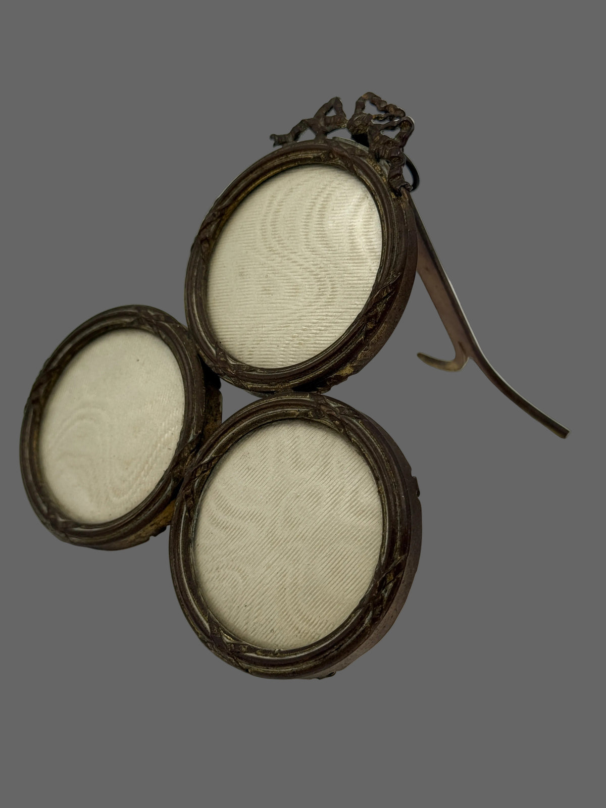 Three round vintage picture frames with dark brown ornate metal frames and off-white mesh screens, arranged on a white surface against a light gray background.