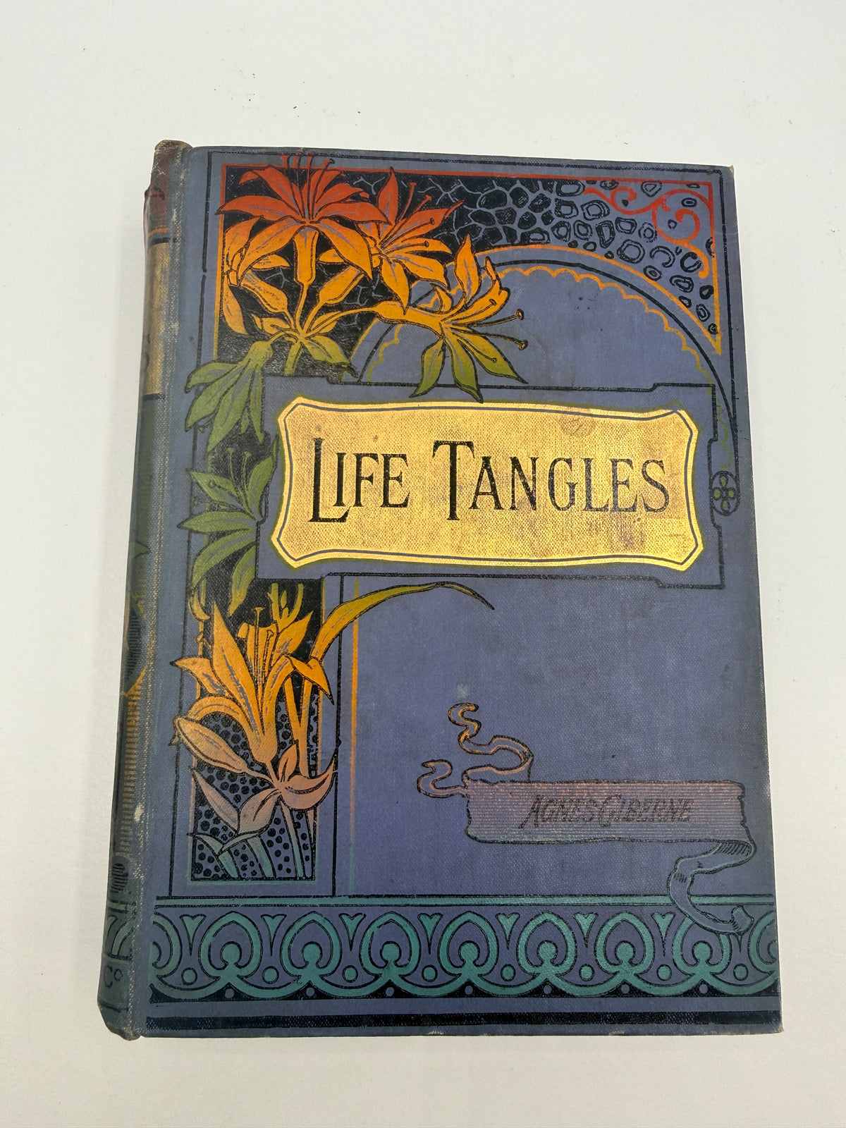 Vintage hardcover book titled 'Life Tangles' by Agnes Osborne, featuring an ornate blue cover with yellow and orange floral illustrations and a gold-toned title plaque.