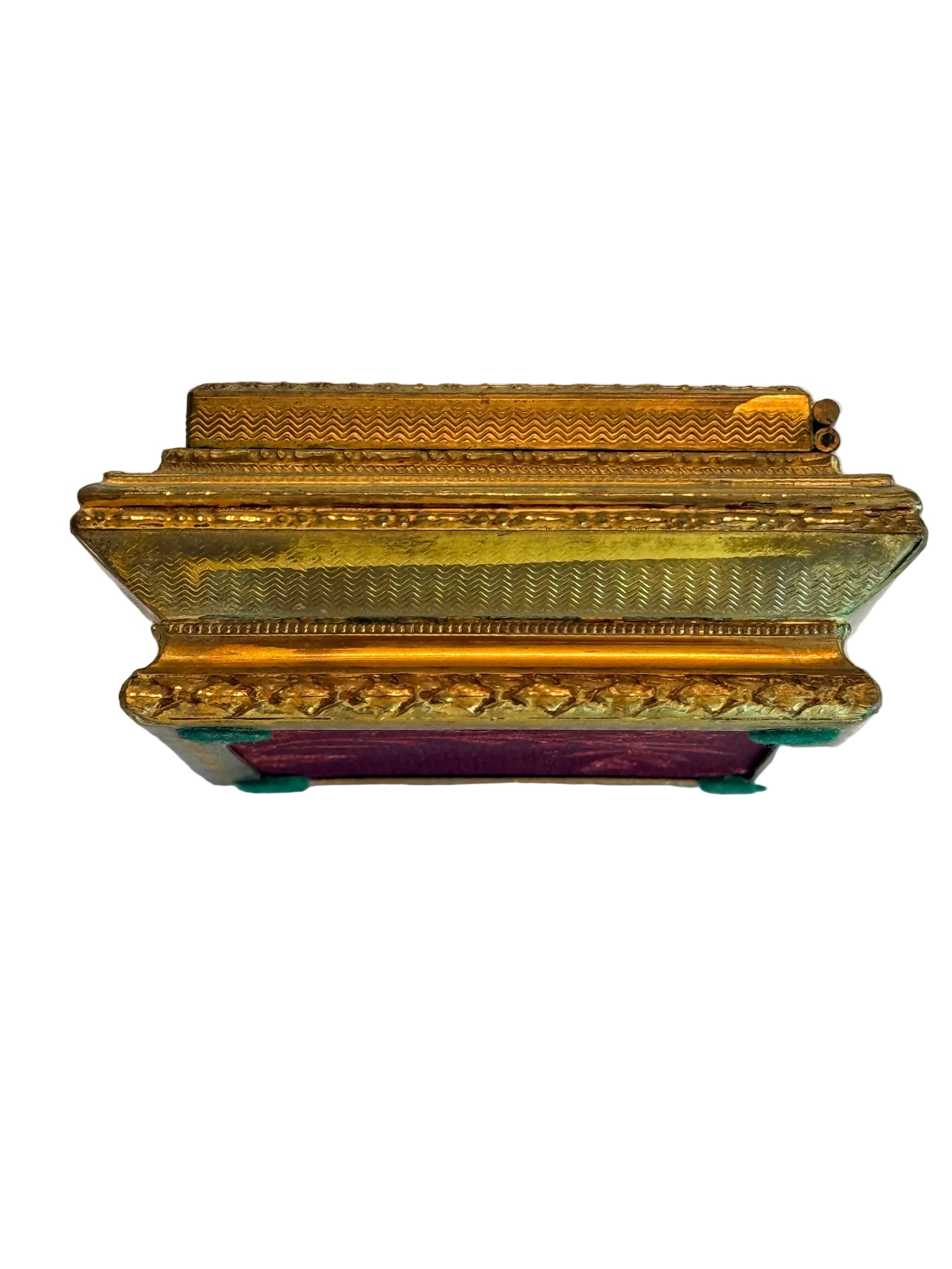 Decorative gold box with intricate designs on a white fabric background