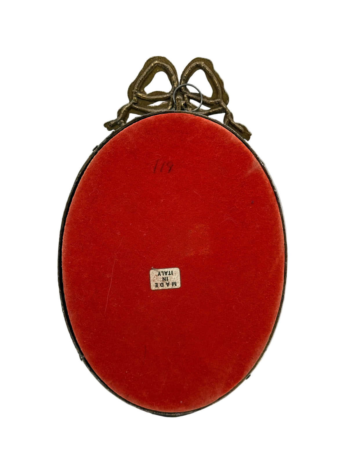 An oval-shaped vintage red velvet case with a dark brown leather trim and ornate bronze-colored handles at the top, featuring a small white paper label that reads 'MADE IN ITALY'.