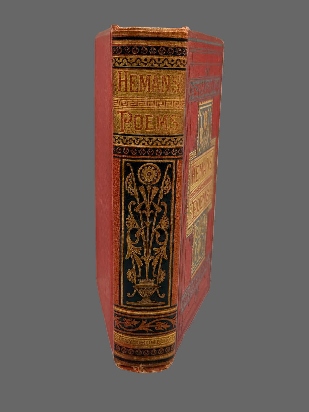 A vintage hardcover book titled 'Hemans Poems' standing upright on a white surface against a white background. The book features a red cloth binding with ornate gold and black decorative tooling on the spine and cover.
