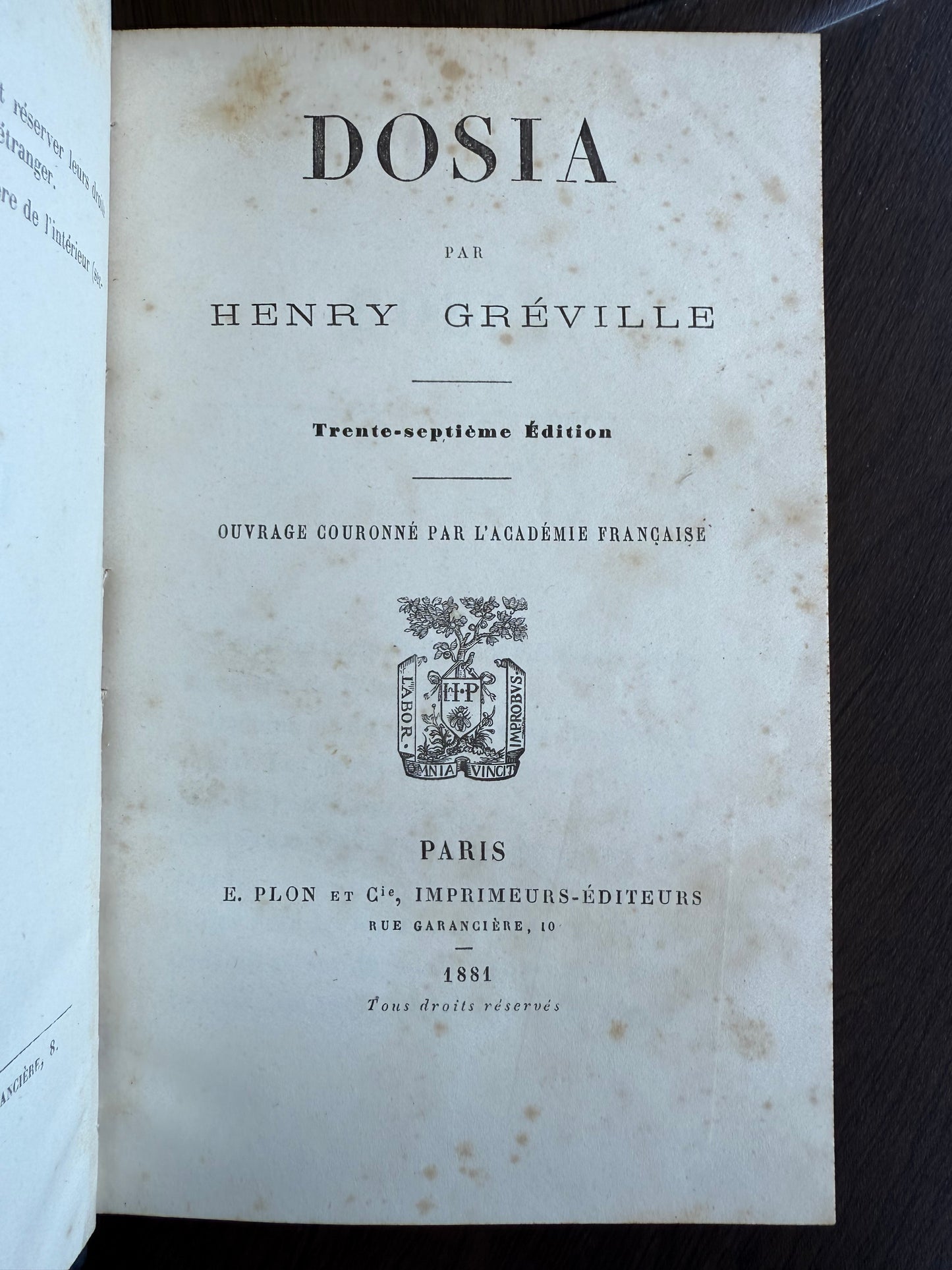 Title page of a vintage book with text and a logo on a dark background