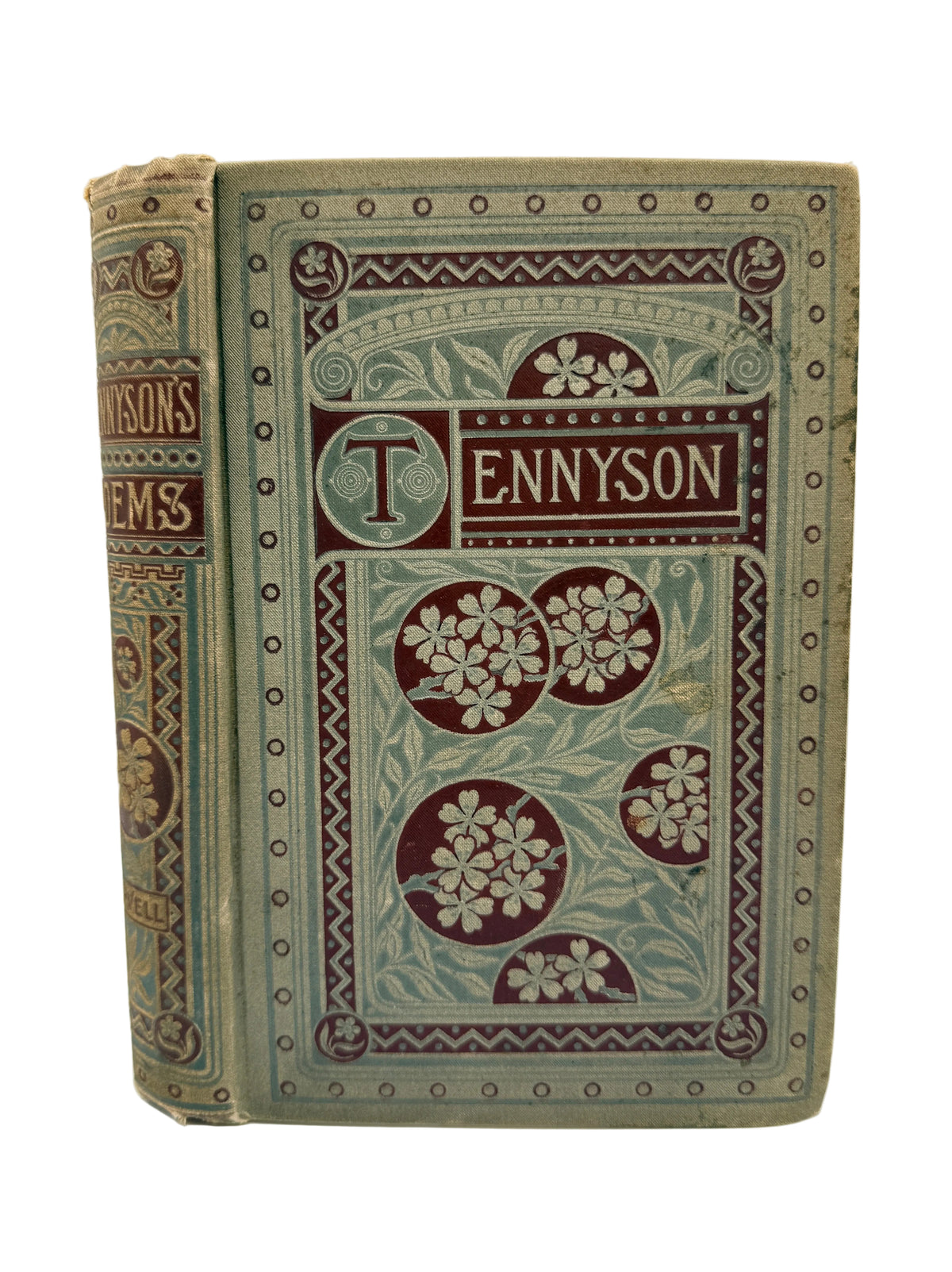 An antique hardcover book titled 'Tennyson' with ornate floral and geometric embossed decoration in muted green, burgundy, and tan tones, photographed upright against a plain light background.