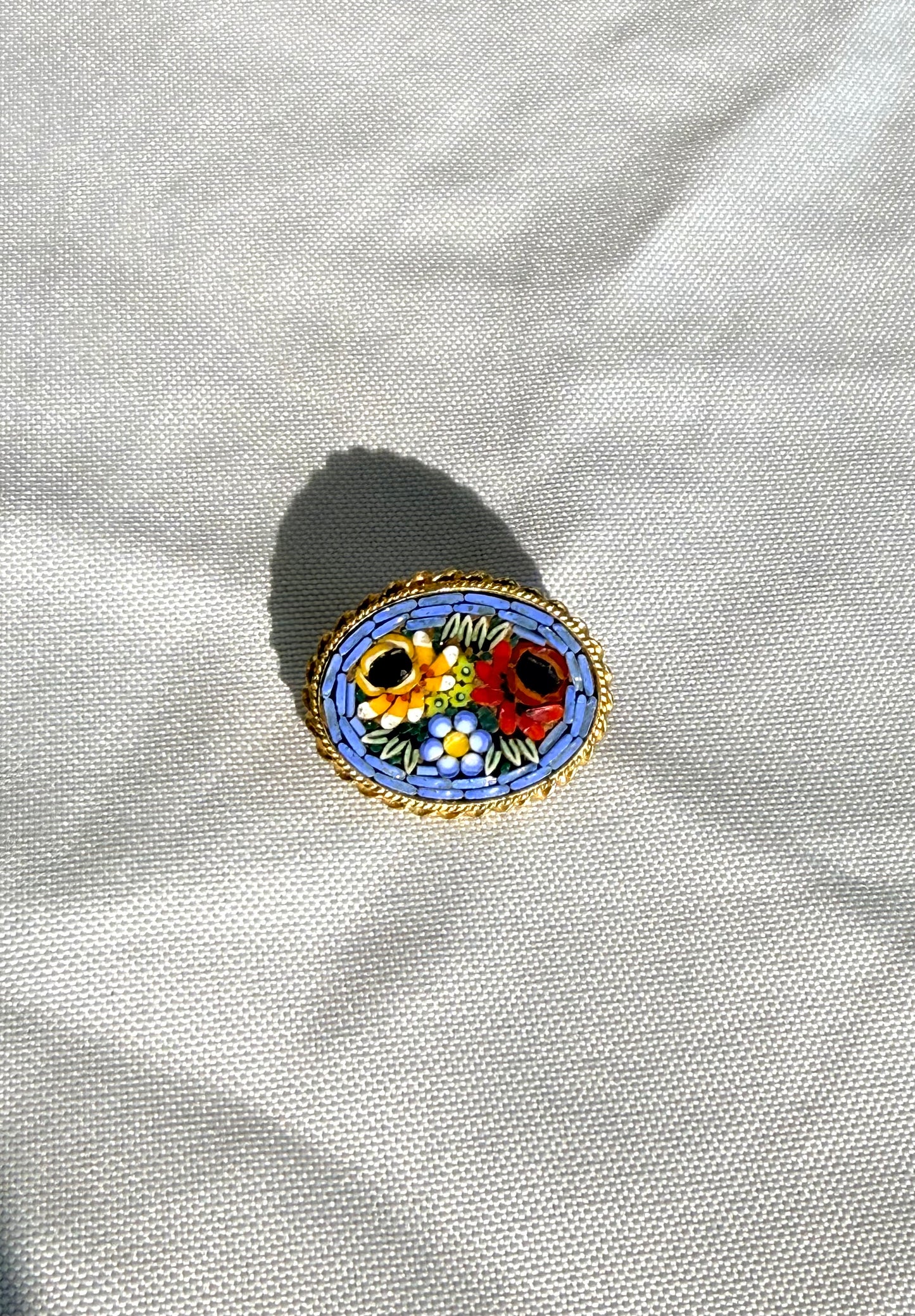 Decorative brooch with floral design on a white fabric background.