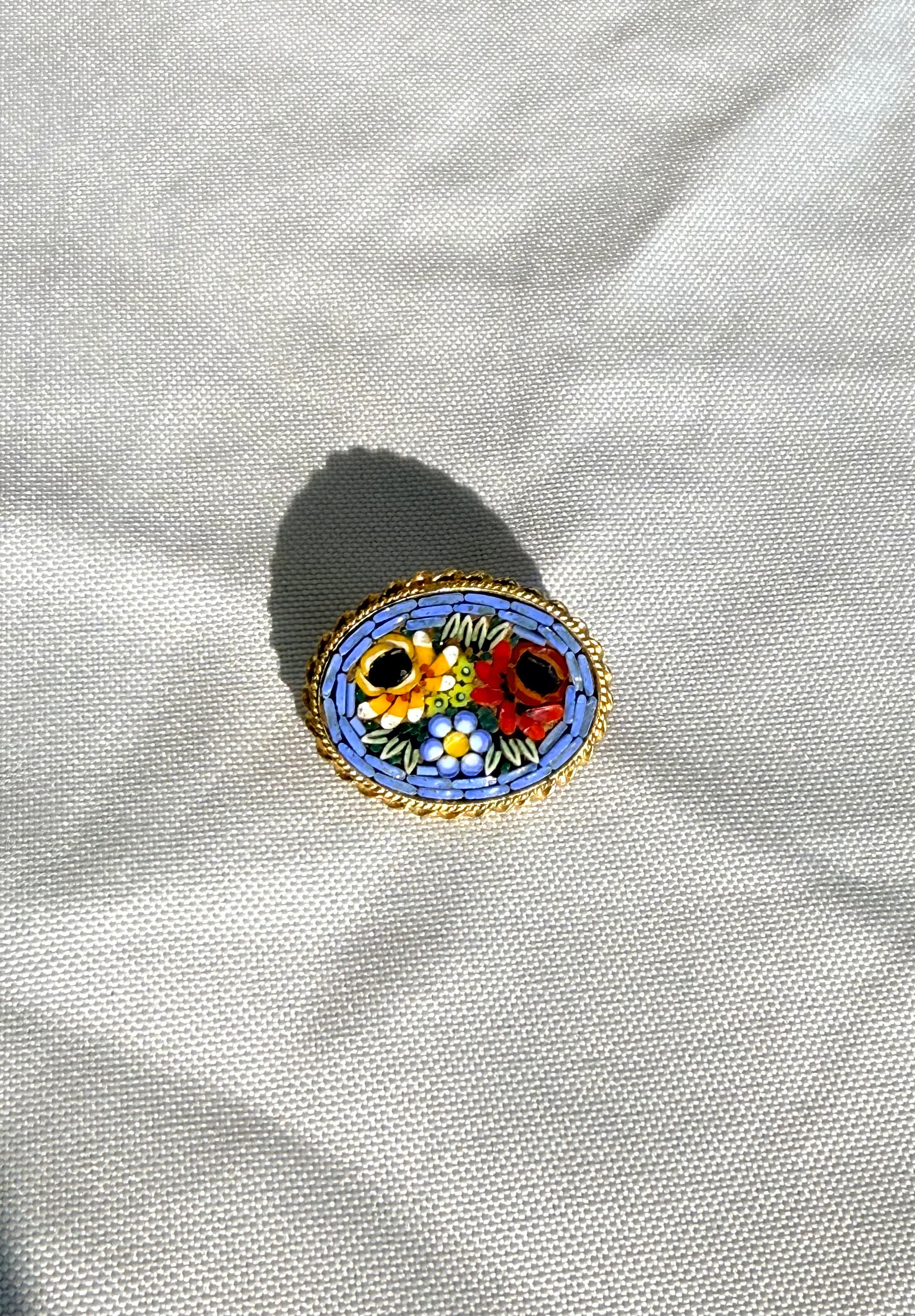 Decorative brooch with floral design on a white fabric background.