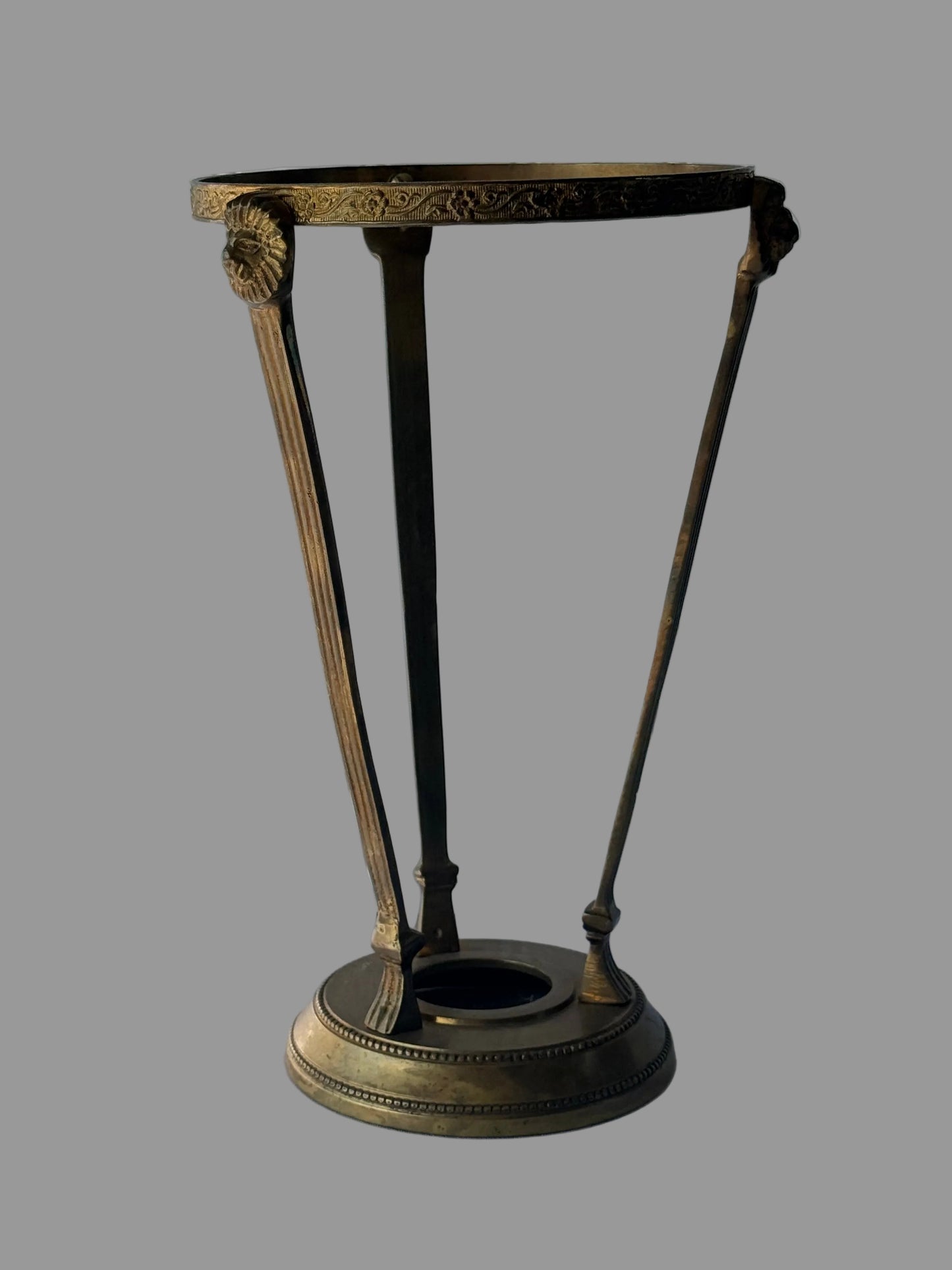 A brass metal stand with lion faces on the side 