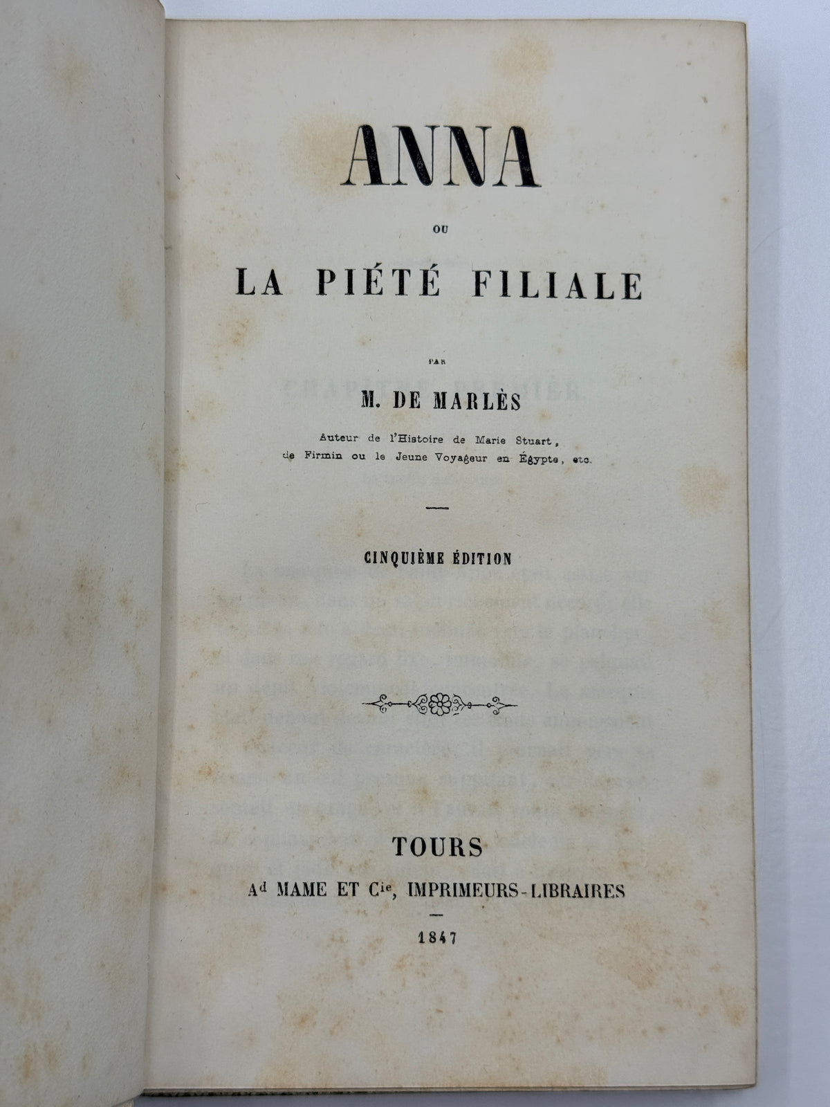 An open vintage book showing the title page in French, reading 'ANNA DE LA PIÉTÉ FILIALE' with publisher text 'TOURS A MAME ET C , IMPRIMEURS-LIBRAIRES 1847' on aged cream paper.