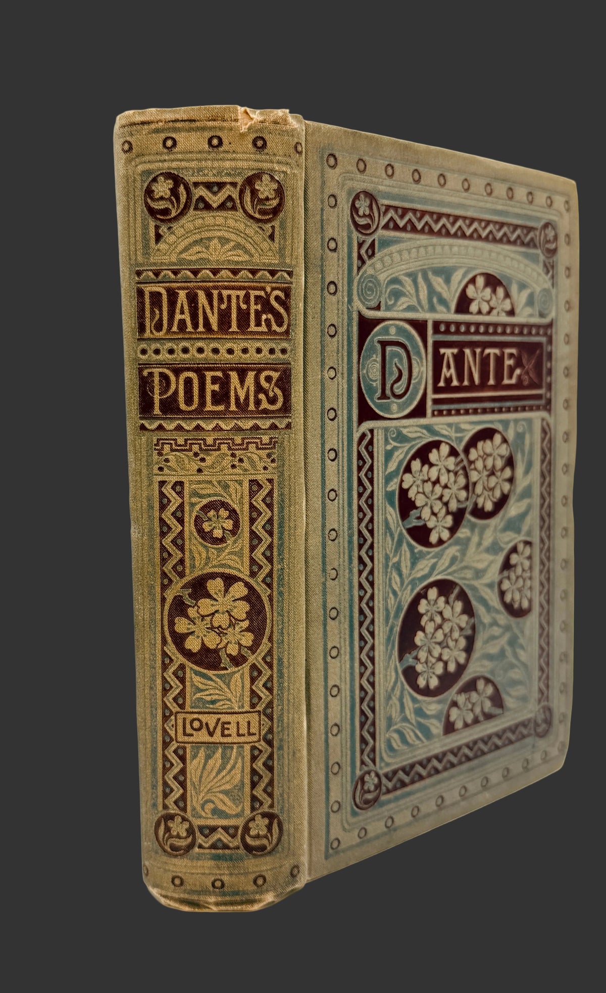 An antique hardcover book titled 'Dante's Poems' by John Keats, published by Lovell. The book features ornate floral embossed detailing on its tan and brown leather binding, with a blue-gray patterned cover panel on the right side.