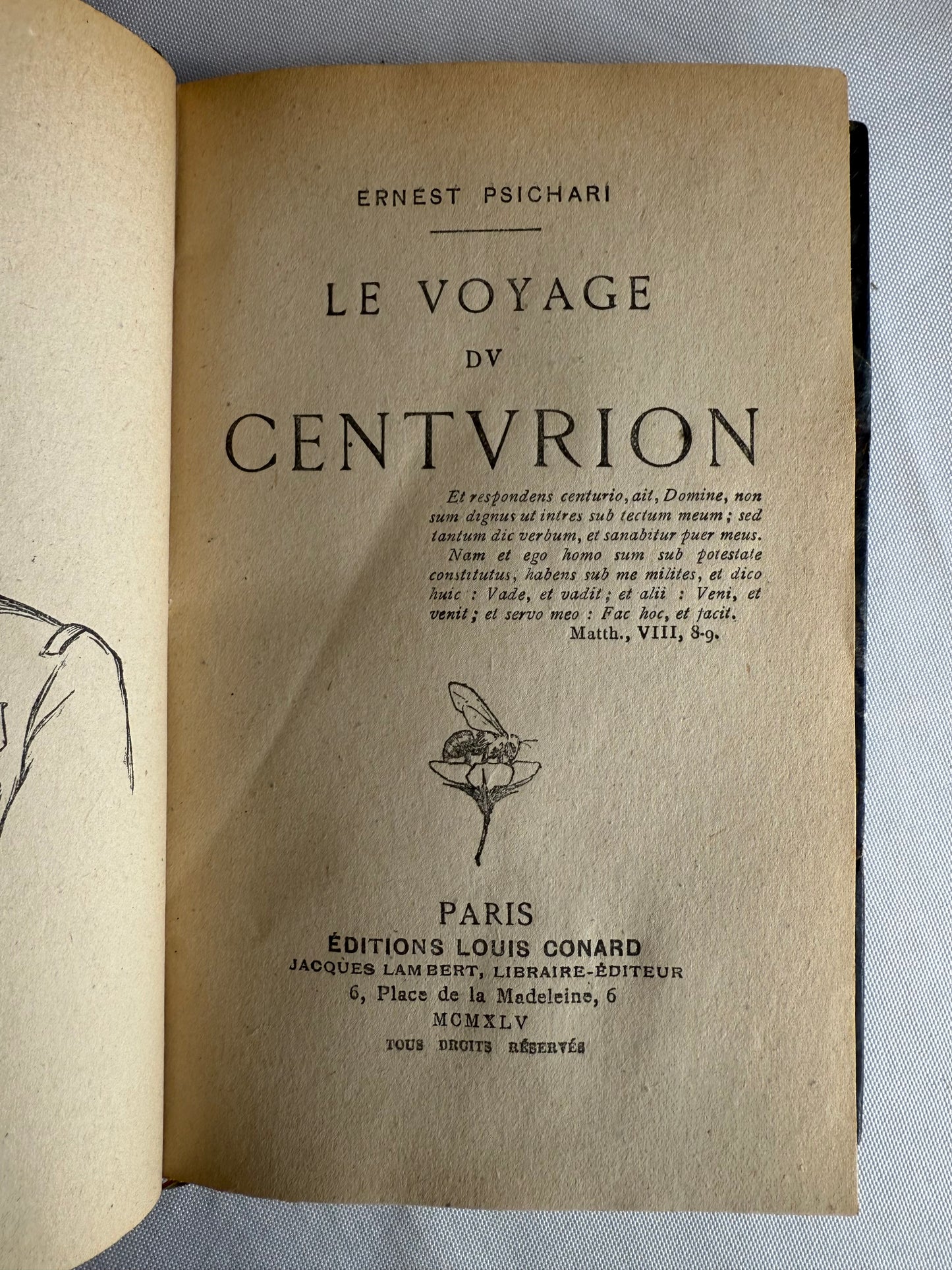 Title page of a vintage book with text and a small illustration on a textured surface.