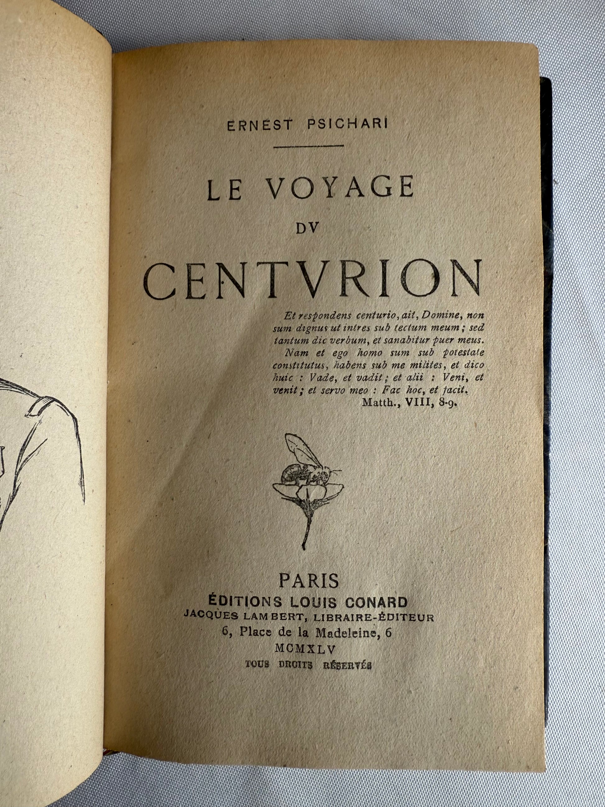 Title page of a vintage book with text and a small illustration on a textured surface.