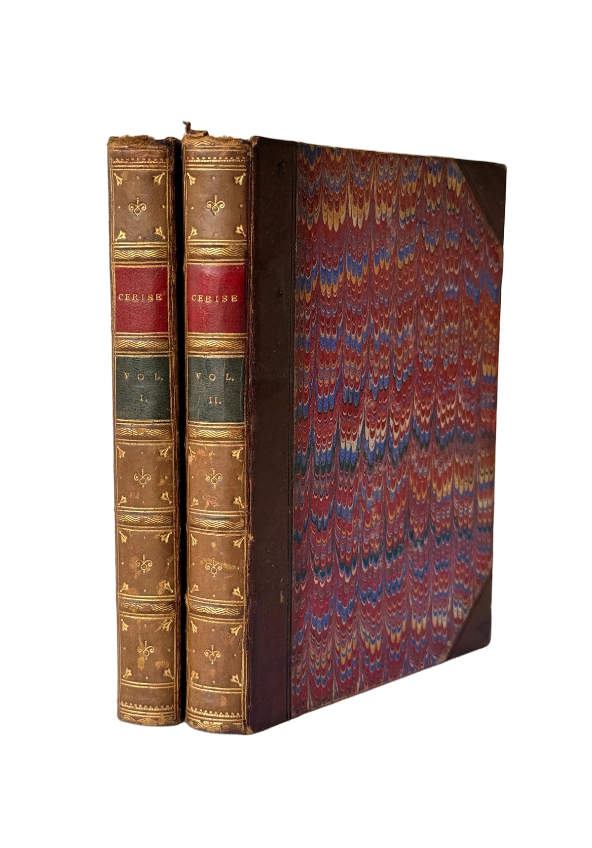 Two antique leather-bound books standing upright, showing their brown gilded spines and marbled red, blue, and gold paper covers, set against a light gray paneled background.