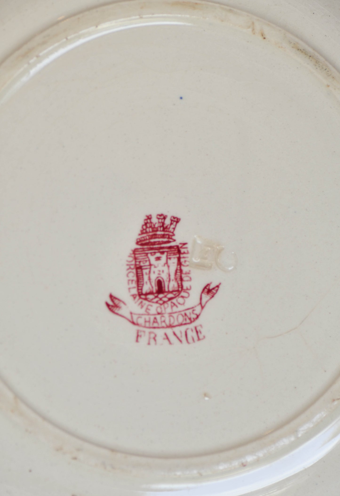 Close-up of a red logo and text on a white ceramic plate.