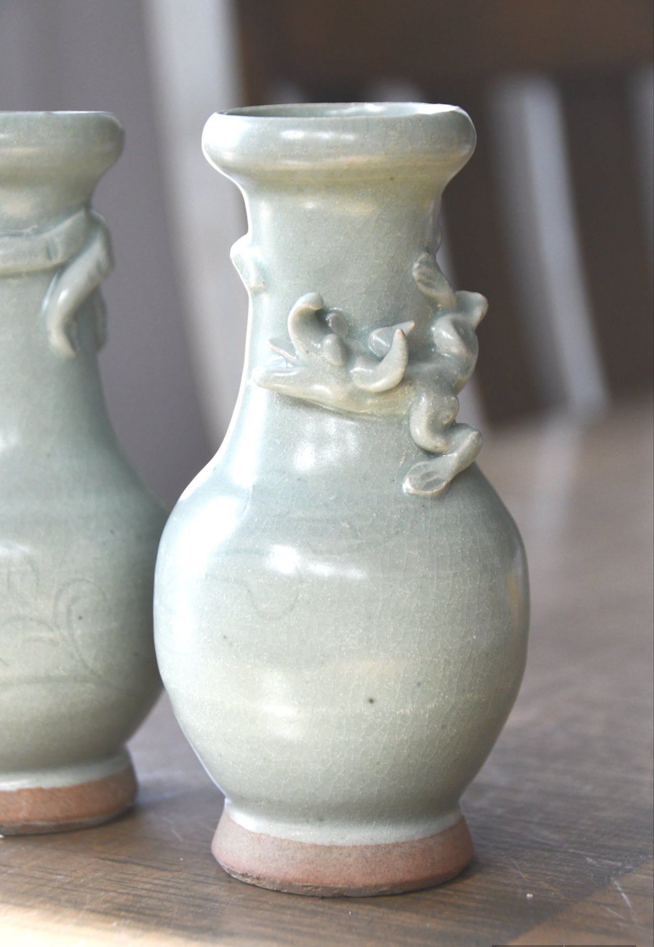 Two ceramic vases with decorative elements on a wooden surface
