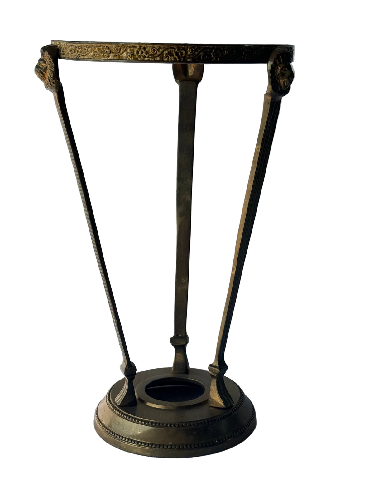 An antique-style bronze metal stand with a circular base, three angled legs, and an ornate top frame, photographed against a white paneled wall.