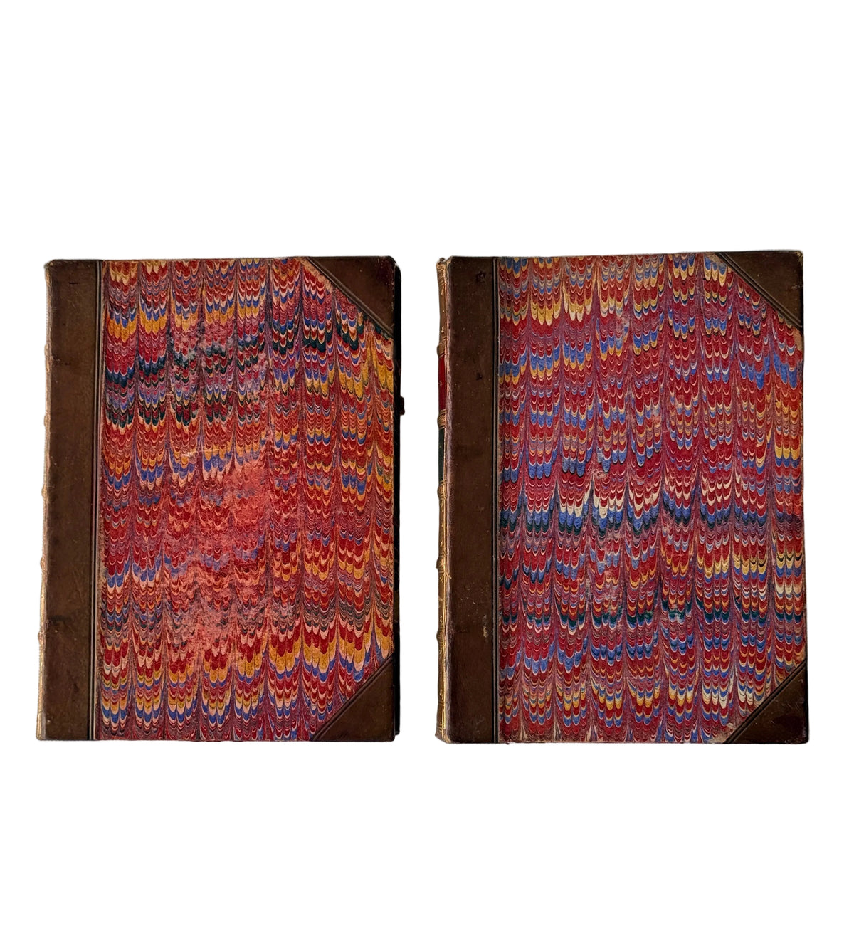 Two vintage hardcover books with marbled paper covers in red, orange, yellow, and blue, displayed side-by-side on a light gray background.