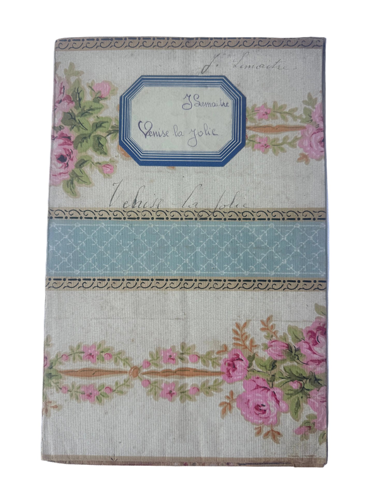 A vintage French pocket watch box or notebook cover with a floral rose pattern, a blue patterned label, and a central light blue horizontal stripe, shown on a light blue background.