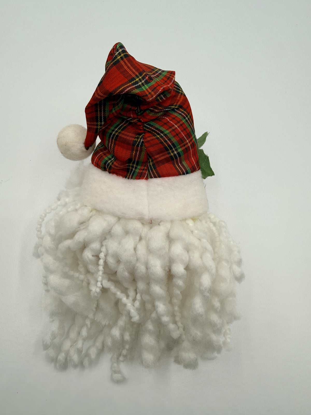 A small Santa hat and beard decoration on a plain white background. The hat is made of red tartan plaid fabric with green and yellow stripes, featuring a white pom-pom and white faux fur trim.