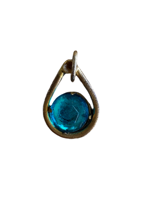 Gold necklace pendant with a blue gemstone on a white background