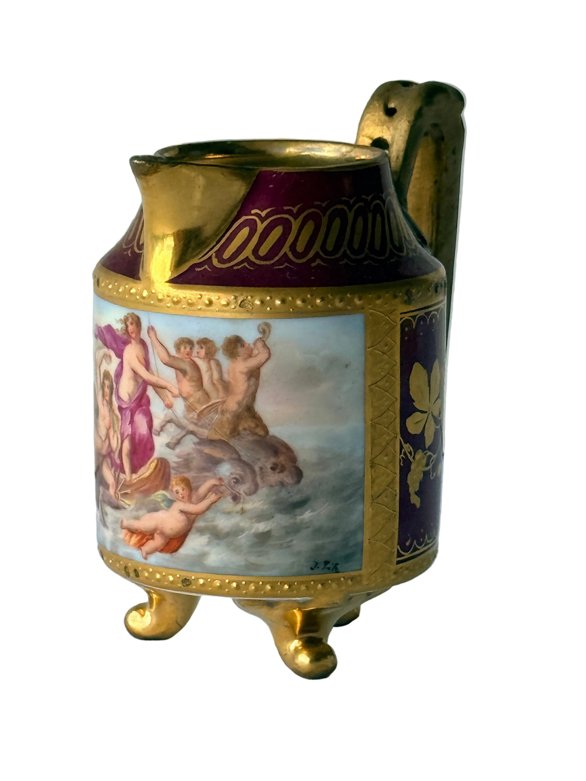 An ornate vintage porcelain pitcher with gold gilding, a purple band with gold lettering, and a central classical painting depicting figures in clouds, set against a light gray paneled background.