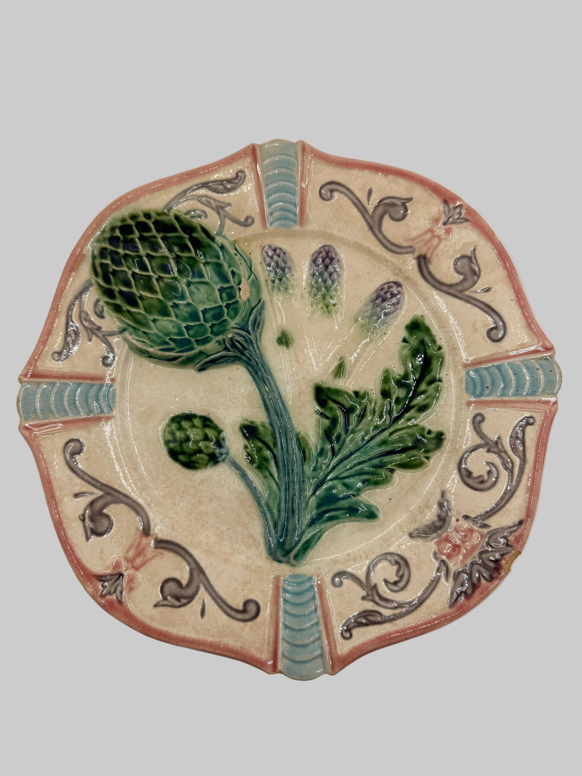 A decorative ceramic wall plaque featuring a raised 3D botanical design of an artichoke and leaves on a beige background, surrounded by a scalloped border with blue-green and terracotta details.