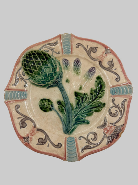 A decorative ceramic wall plaque featuring a raised 3D botanical design of an artichoke and leaves on a beige background, surrounded by a scalloped border with blue-green and terracotta details.