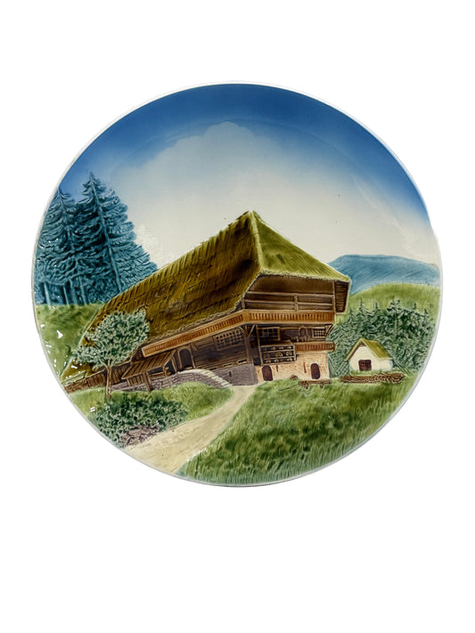 Decorative plate with a mountain cabin and landscape design on a plain background