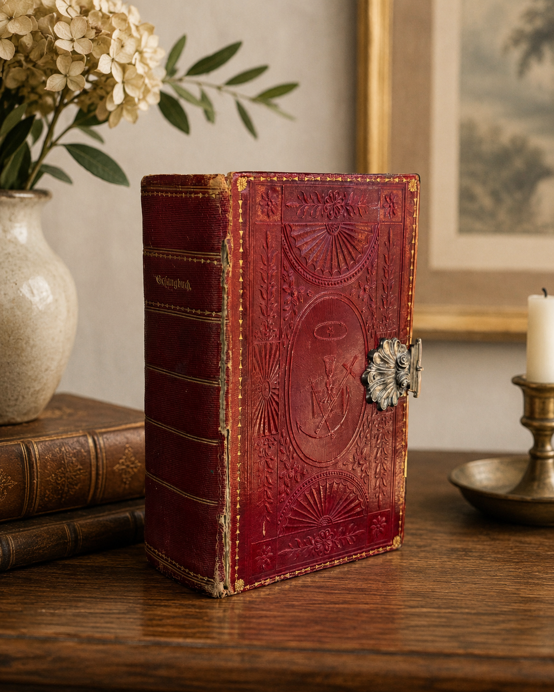 Vintage red leather-bound book with intricate embossing on a wooden surface with decorative elements.