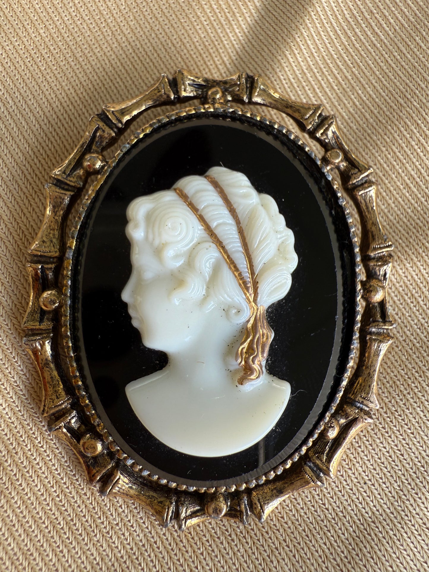 Cameo brooch with a gold frame on a beige fabric background
