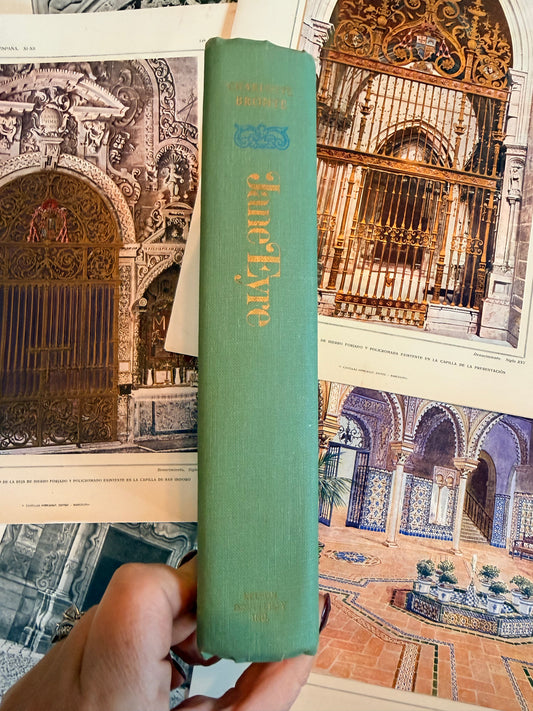 Green book titled 'Jane Eyre' held over vintage architectural illustrations.