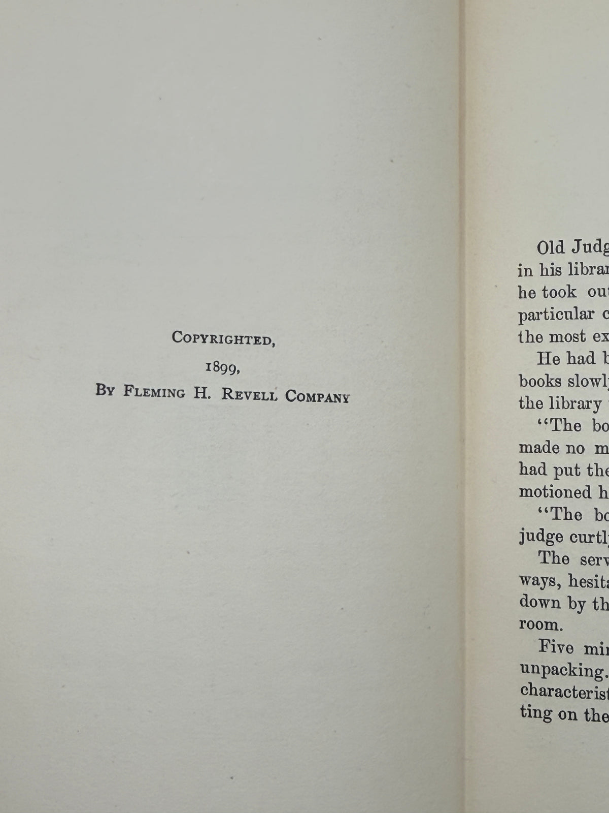 A close-up of an open book showing the copyright page with printed text reading 'Copyrighted, 1899, By Fleming H. Revell Company' on the left page and continuation text on the right page.