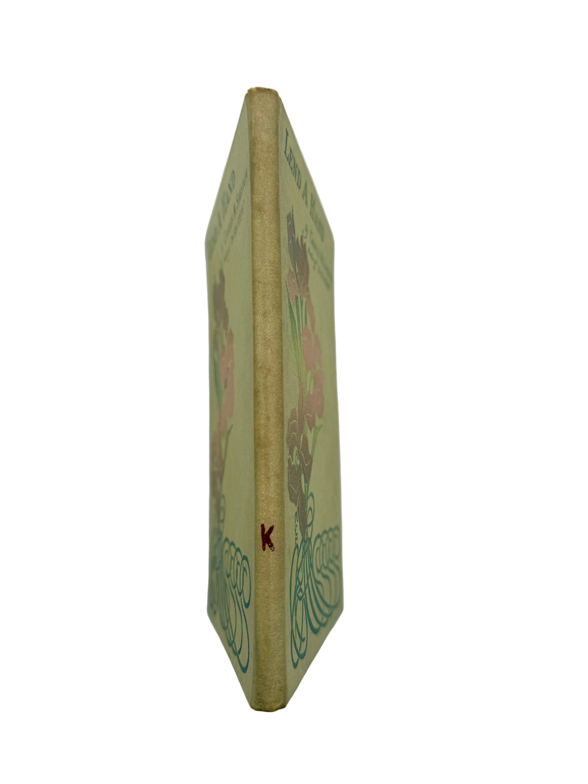 A vintage hardcover book standing upright, showing its illustrated spine in a warm beige tone with floral and wave designs in muted pink and green, photographed against a plain light background.