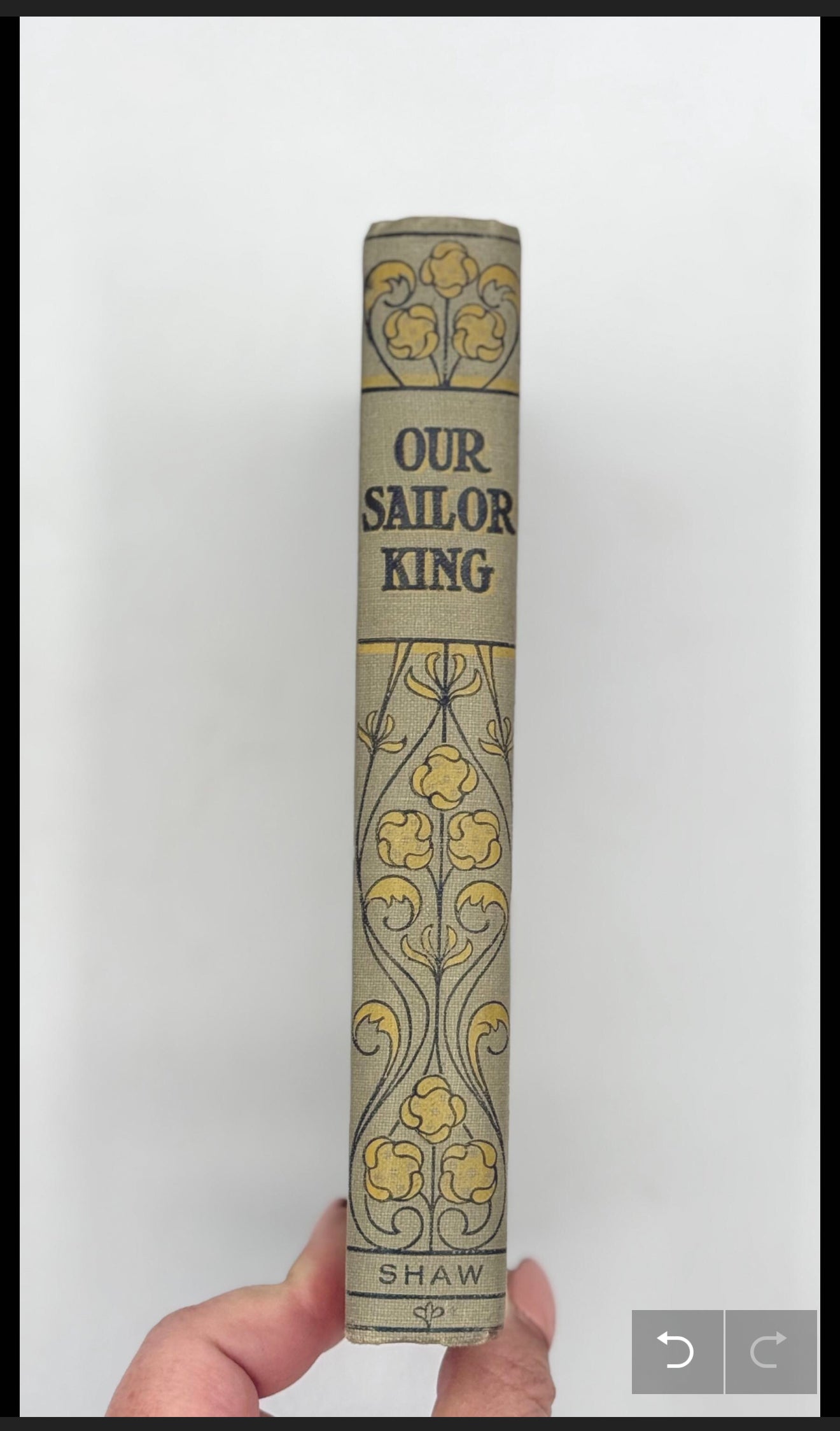 Book titled 'Our Sailor King' by Shaw held against a white background