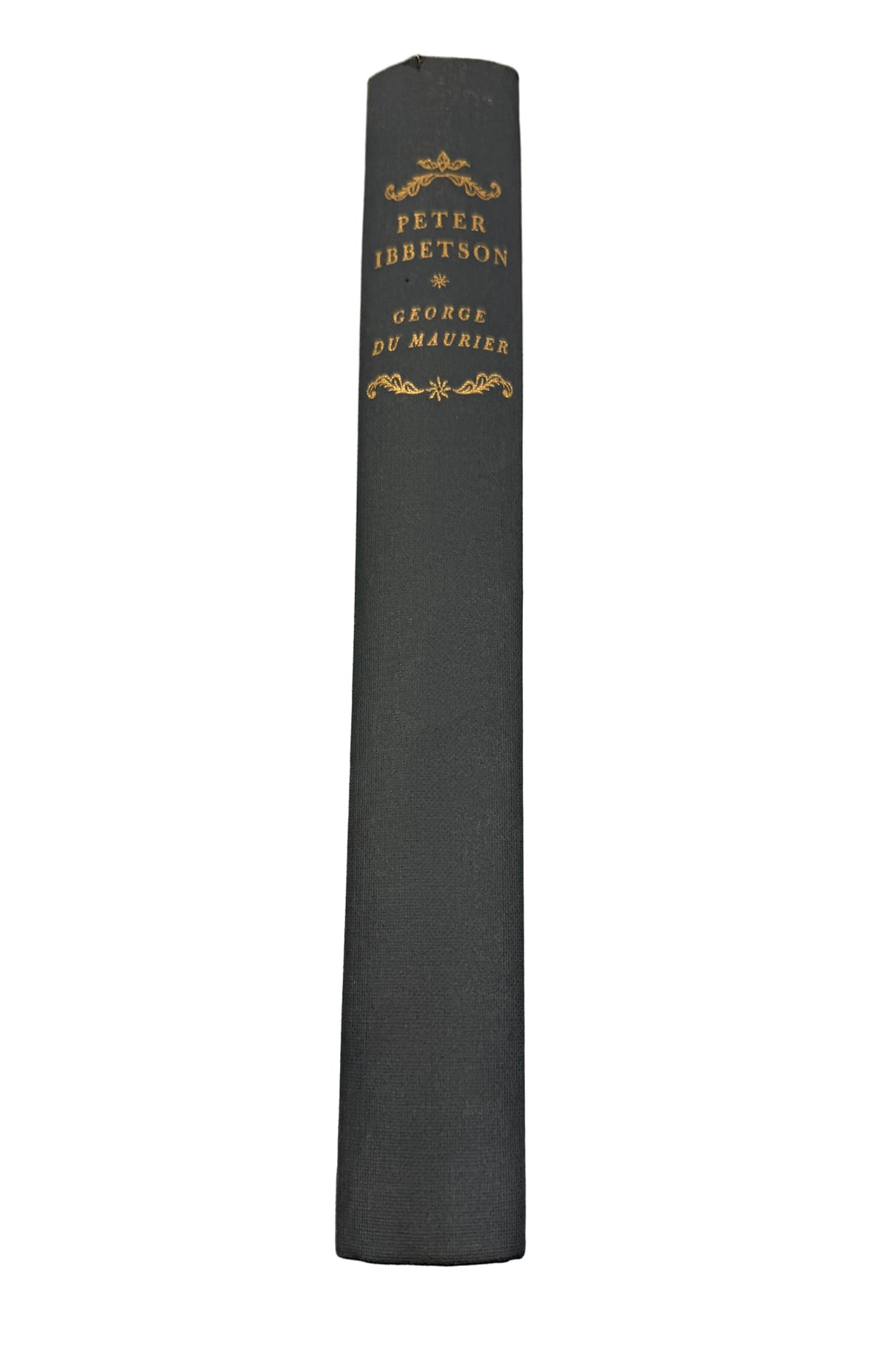 A close-up of a book's dark gray or black spine with gold lettering reading 'PETER IBETSON' and 'GEORGE DE MAURIES', photographed against a white background.