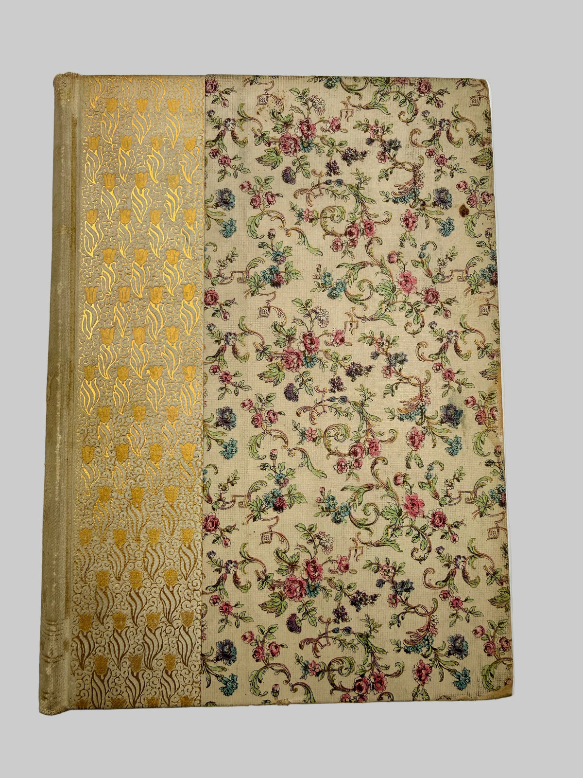 An antique hardcover book with a beige floral tapestry cover and a gold-embossed spine, photographed flat against a white background.