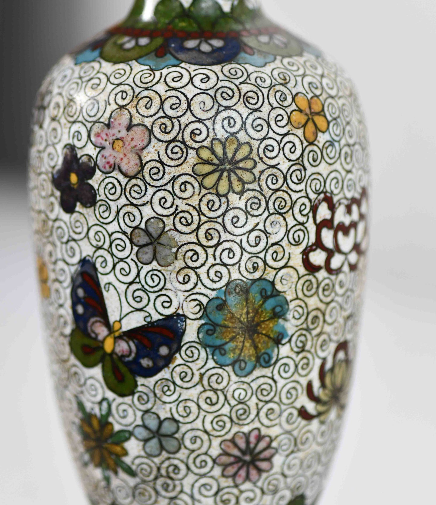 Decorative vase with floral and butterfly patterns on a white background.