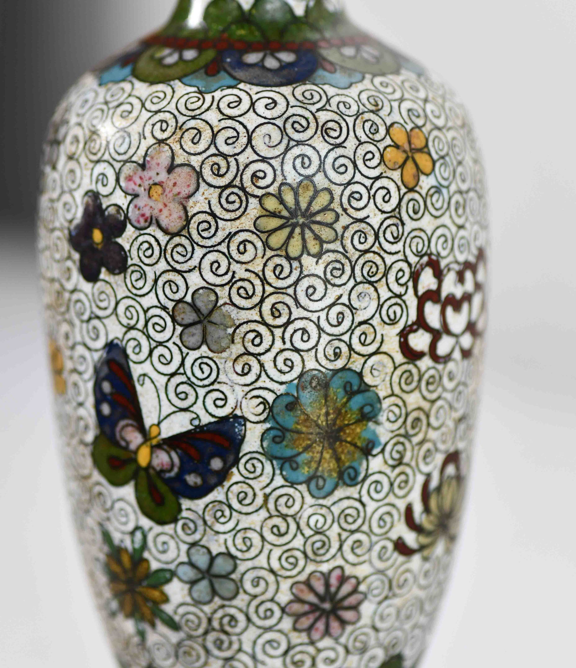Decorative vase with floral and butterfly patterns on a white background.