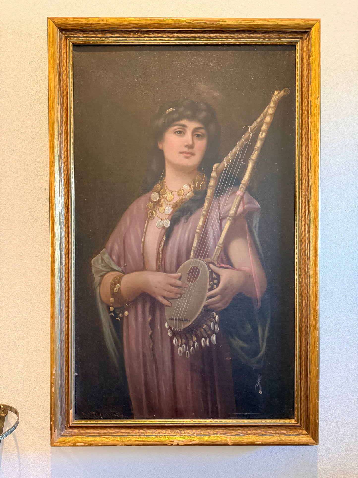 Portrait of a woman holding a harp in a gold frame on a beige wall.