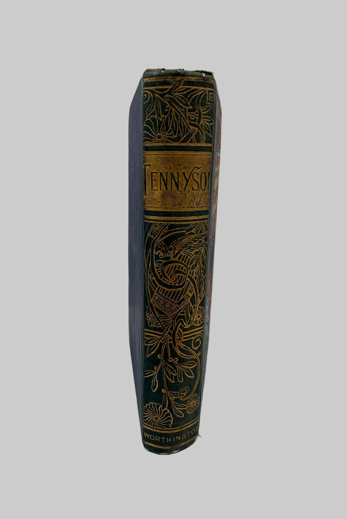 A vintage hardcover book standing upright, showing its dark blue cloth spine with ornate gold embossed floral and scrollwork, and the title 'FENNYSO' printed on a gold label.