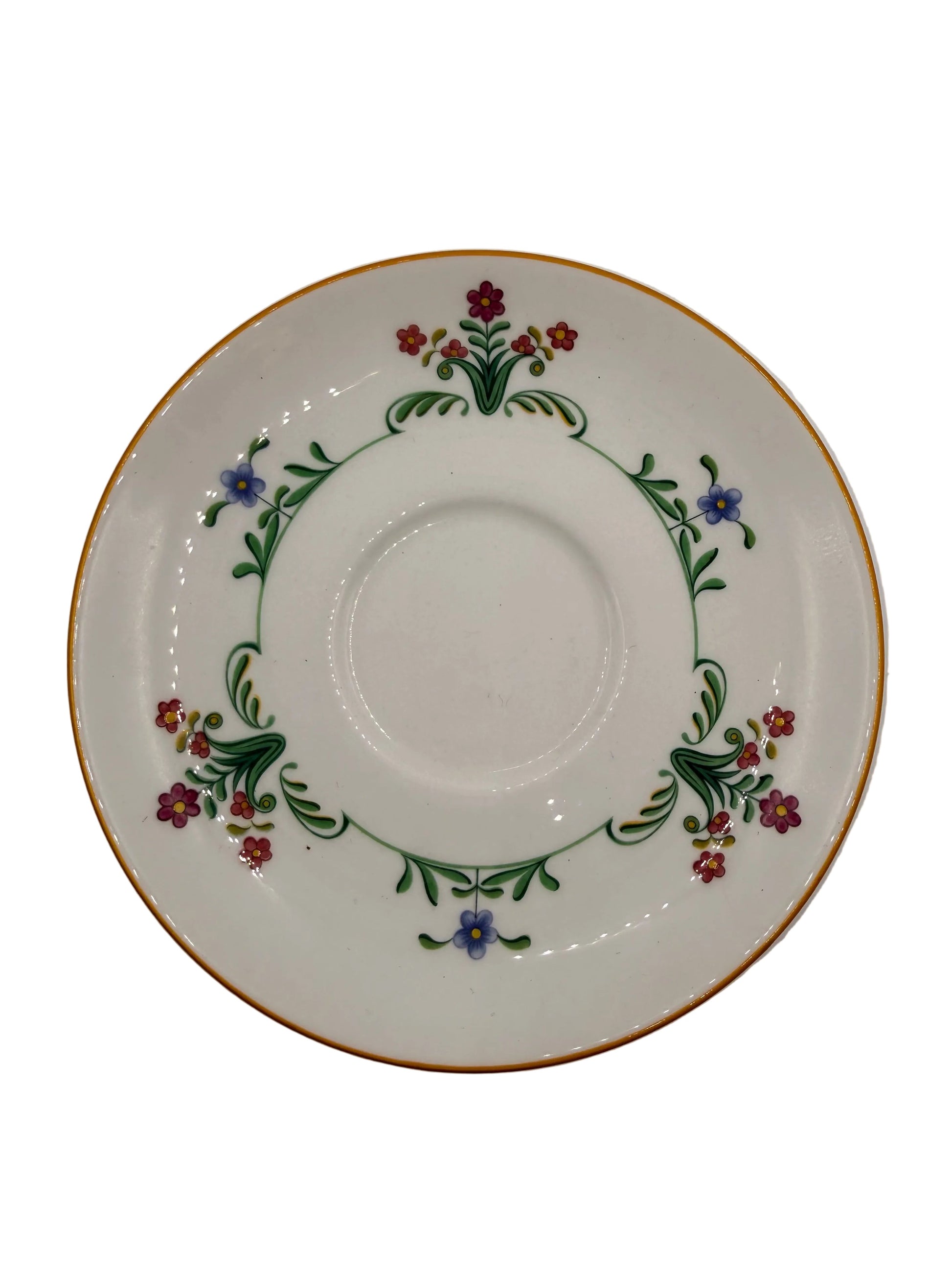 A white porcelain saucer decorated with a delicate floral border featuring green leaves, red and purple flowers, and a thin gold rim, shown on a plain light gray background.