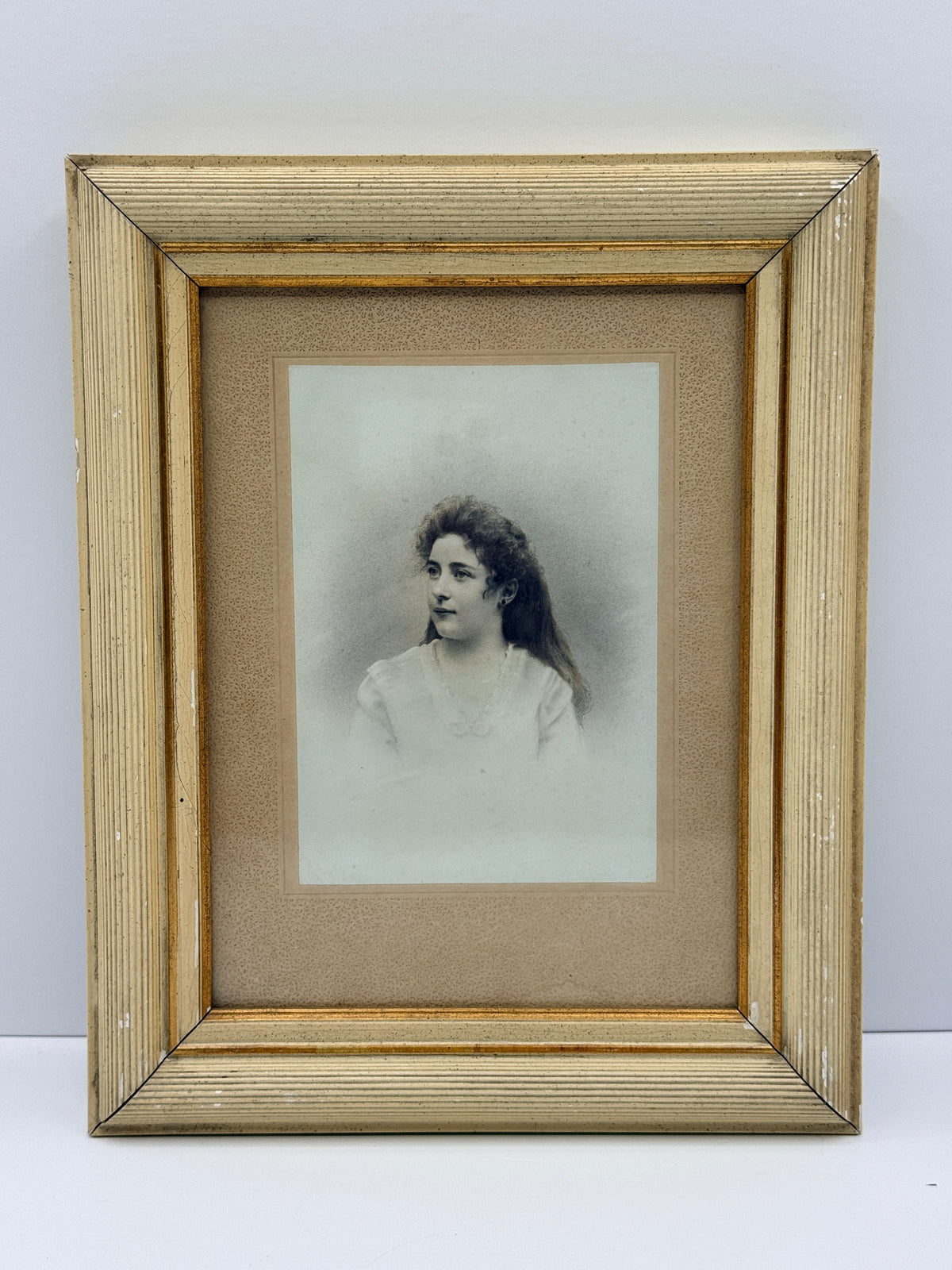 A vintage framed portrait print featuring a sepia-toned sketch of a young woman, matted with tan paper and enclosed in a distressed gold-toned wooden frame against a plain white background.