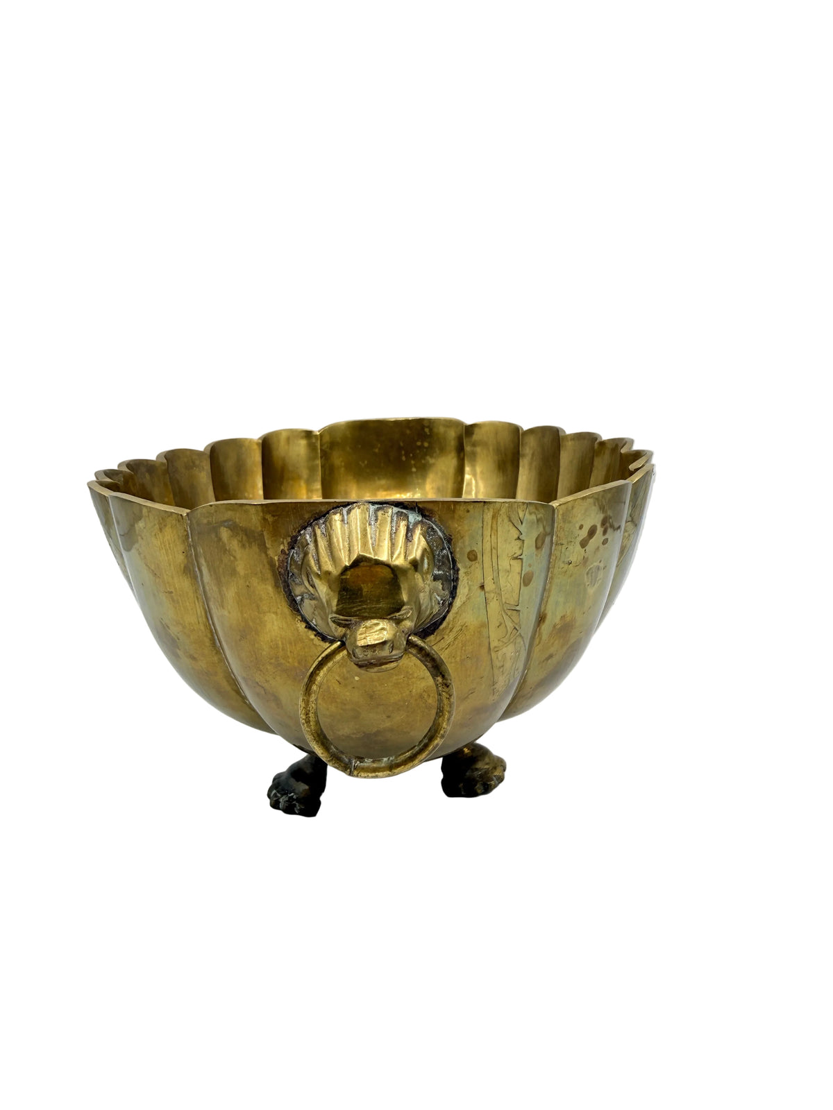 An antique brass or gold-toned metal bowl with a scalloped rim, lion-head ring handle, and small lion feet stands on a white surface against a white background.