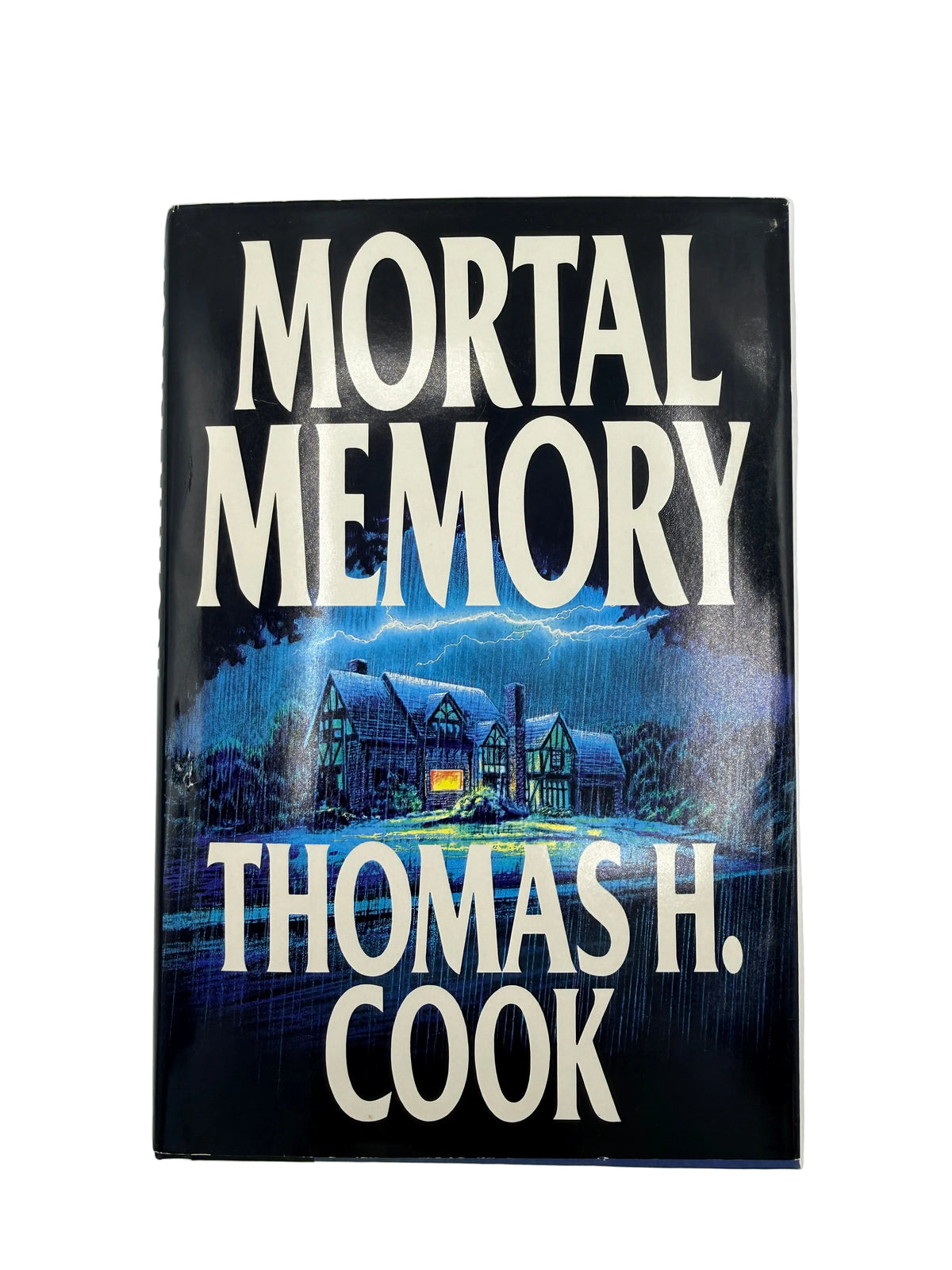 The front cover of the book 'Mortal Memory' by Thomas H. Cook, featuring a dark night scene with a haunted house under a stormy blue sky and large white title text.