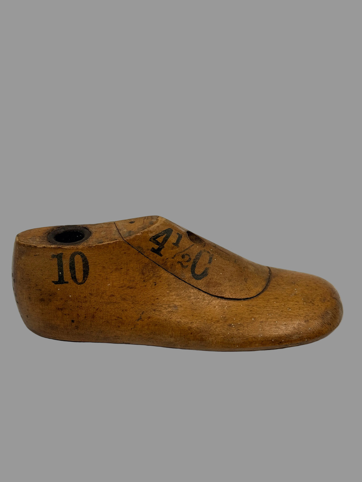 A vintage wooden shoe tree with printed black numbers '10' and '4 1/3' on a light gray background.