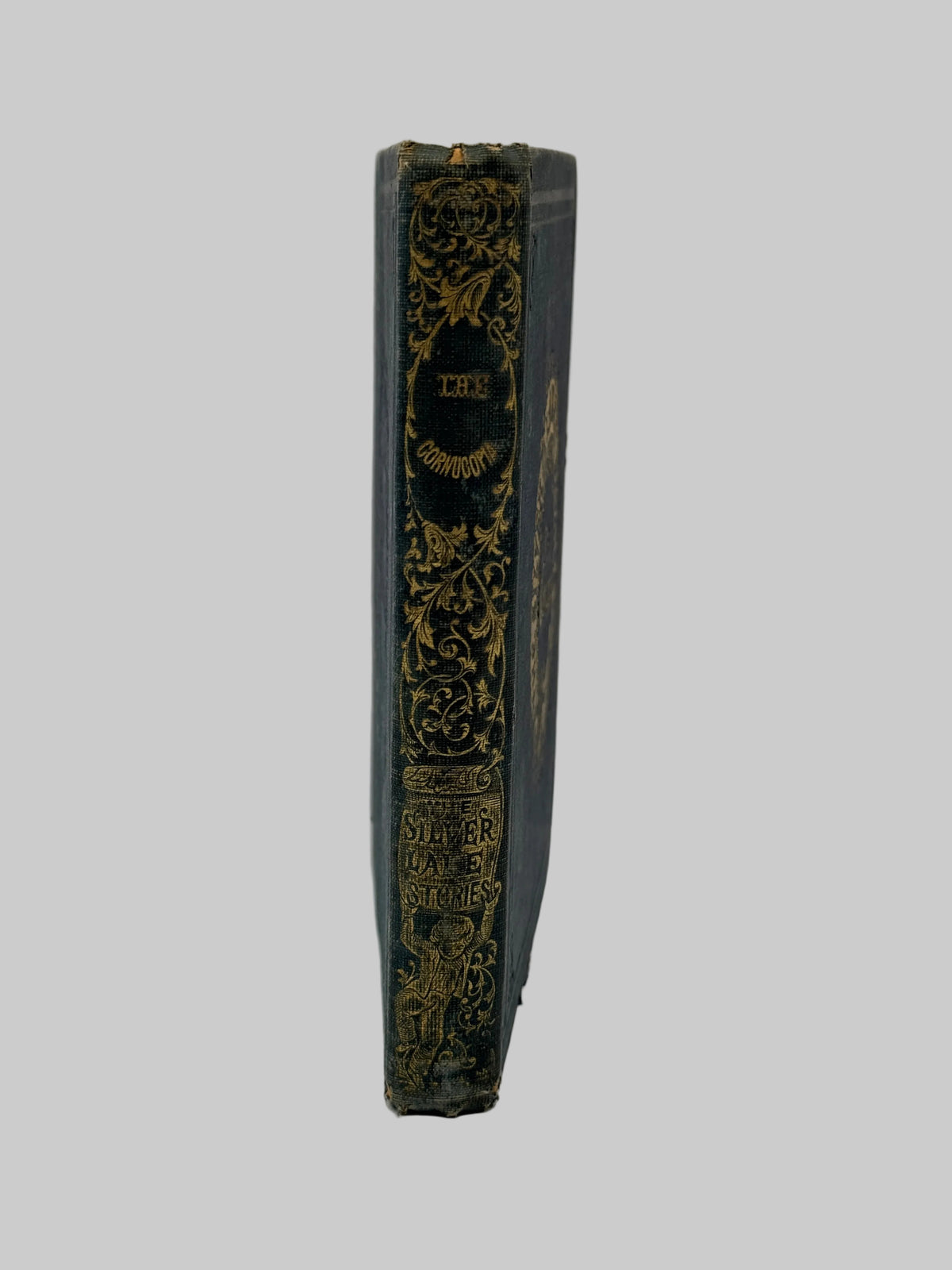 A vintage hardcover book shown from its spine, featuring dark blue-gray cloth with ornate gold gilding and black central label, photographed against a plain white background.