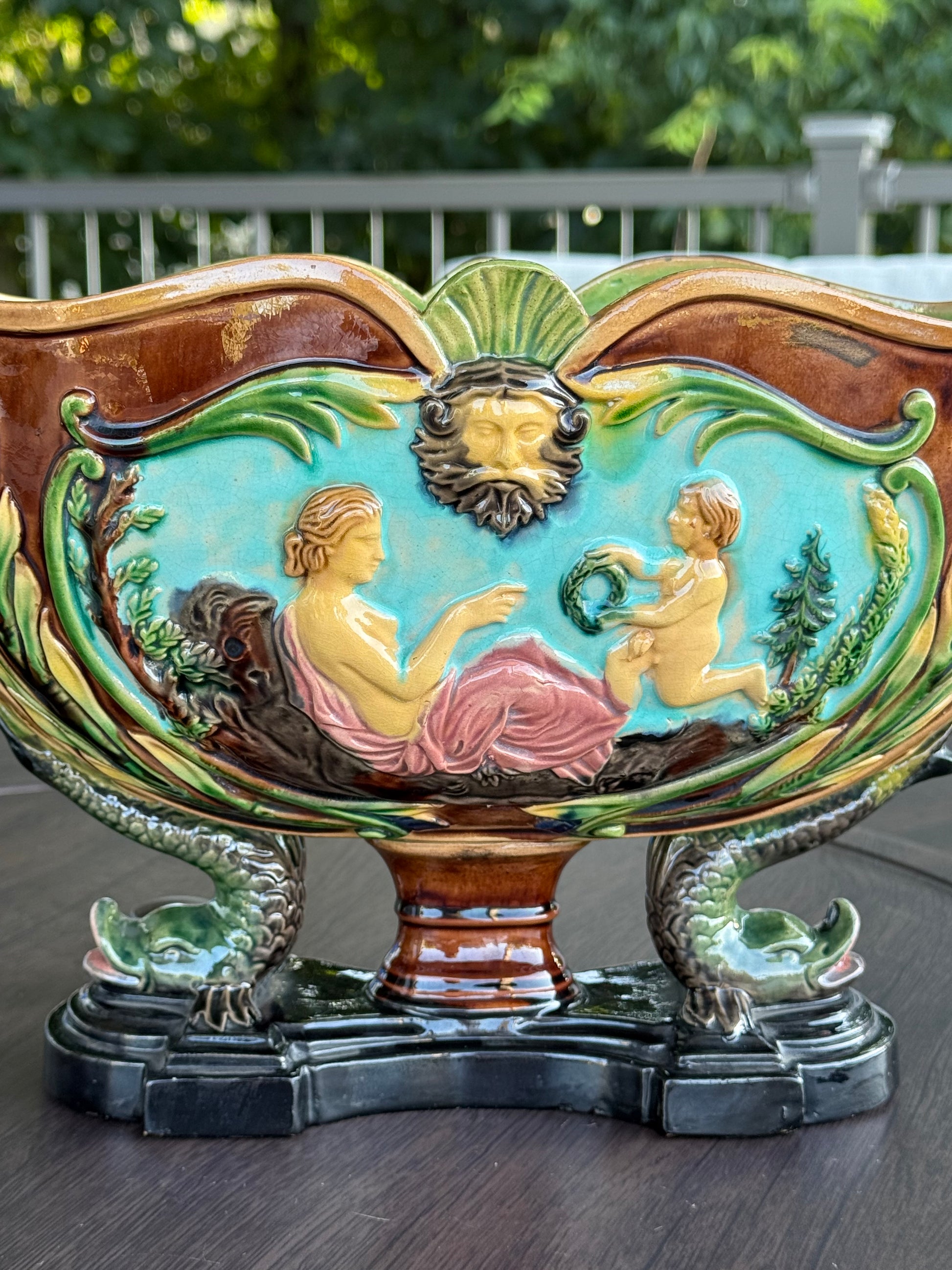 Decorative wall piece with cherubs and a dragon on a wooden background